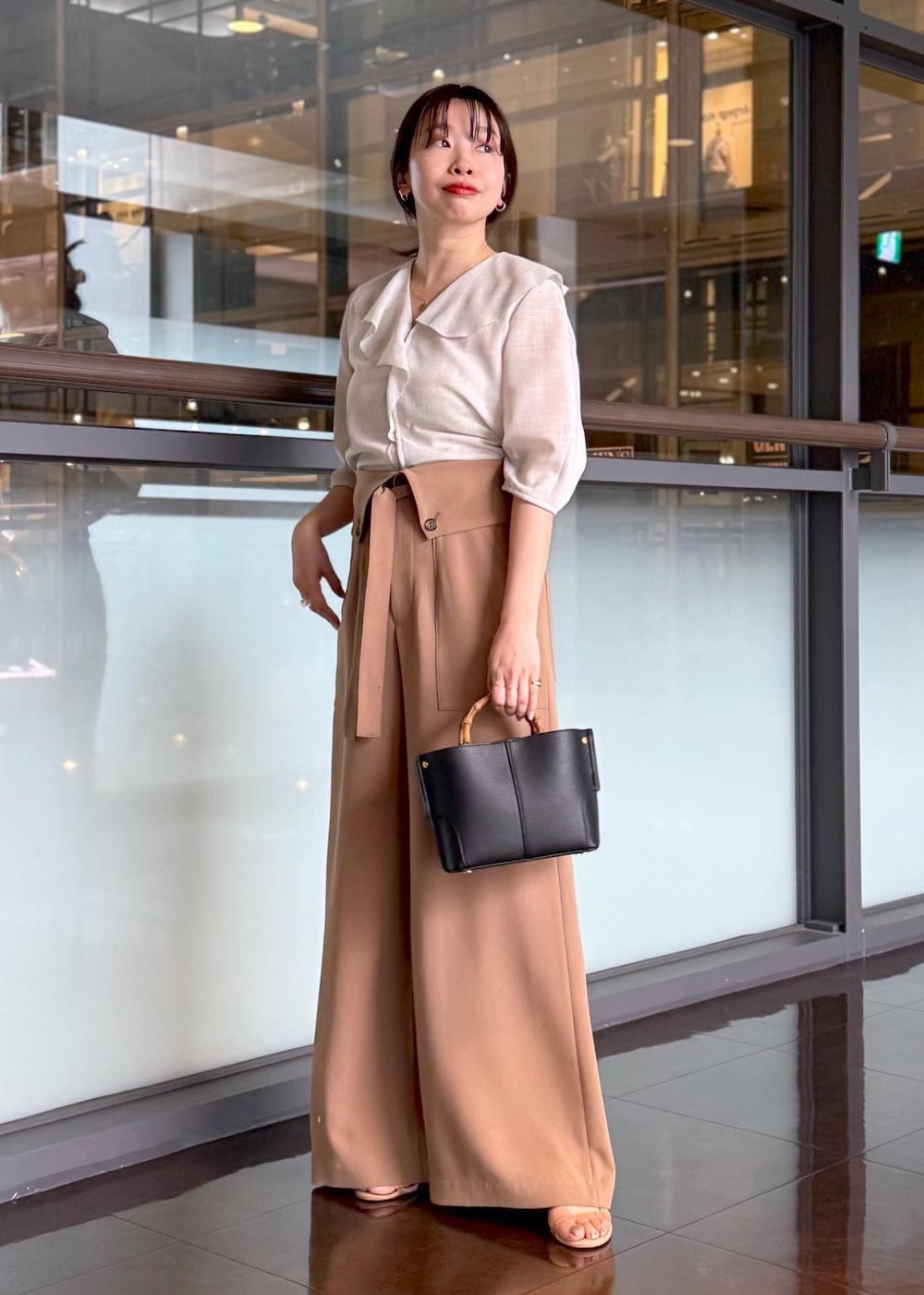 ブラック系のハンドバッグ、ベージュ系のシャツ/ブラウス、ブラウン系のその他パンツを着用したレディースの春コーディネートの2枚目の写真