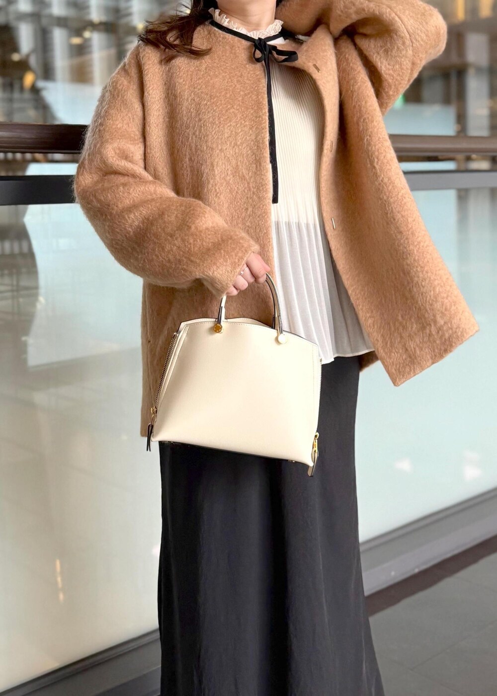 ホワイト系のハンドバッグ、ブラック系のスカート、ホワイト系のシャツ/ブラウスを着用したレディースの秋コーディネートの5枚目の写真
