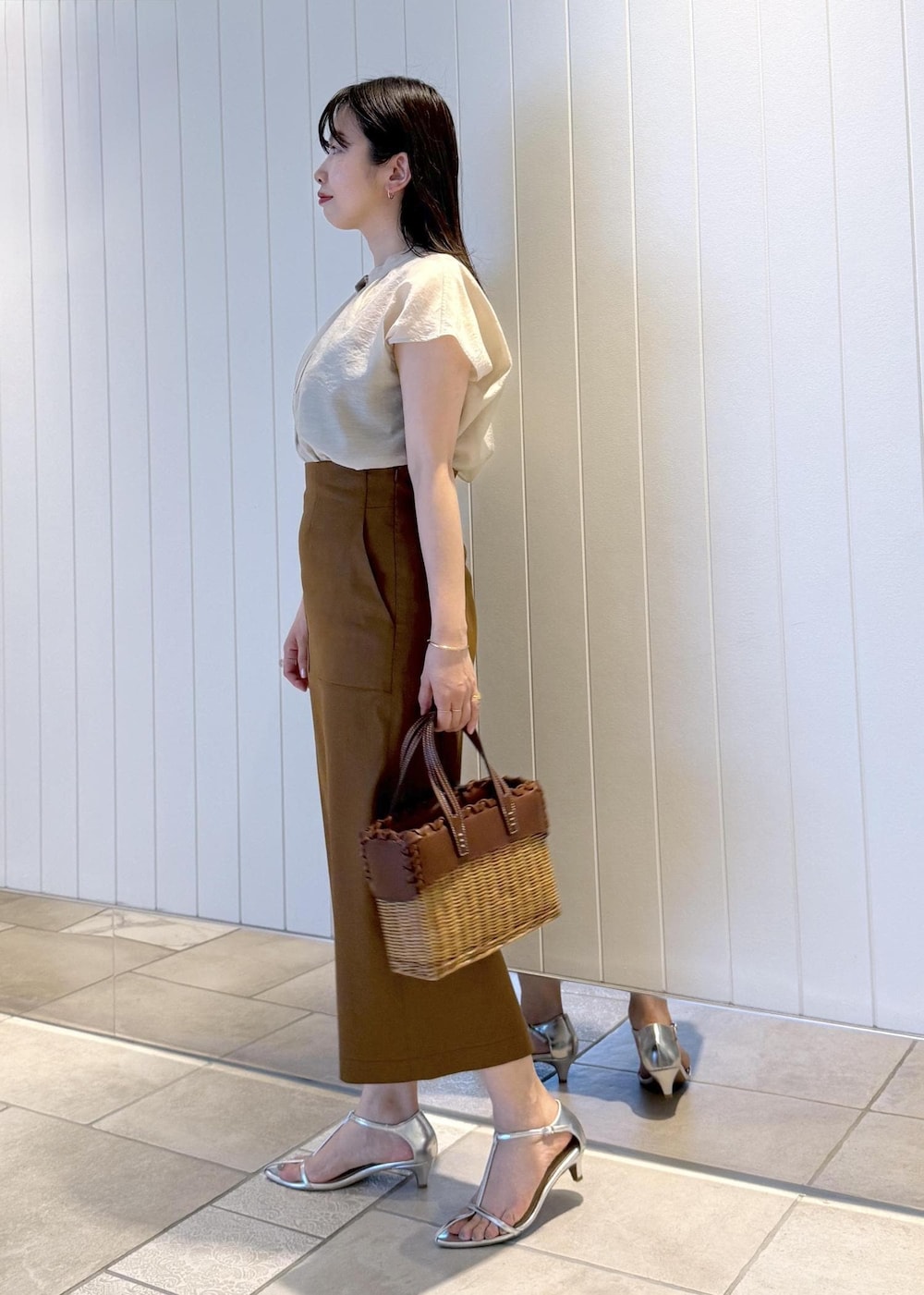 ブラウン系のスカート、ベージュ系のシャツ/ブラウスを着用したレディースの春コーディネートの3枚目の写真