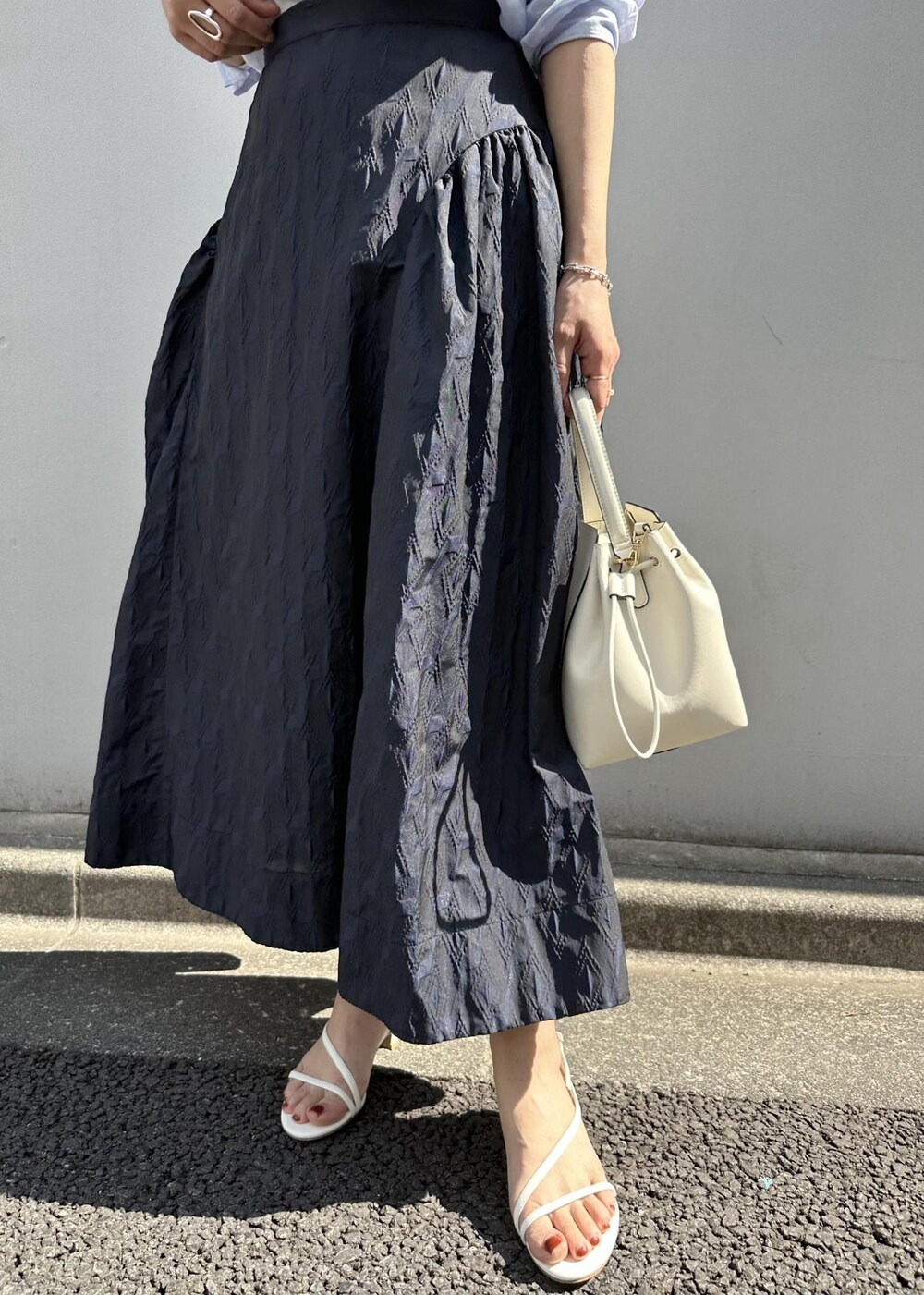 ブルー系のスカート、ブルー系のシャツ/ブラウス、ホワイト系のハンドバッグを着用したレディースの春コーディネートの6枚目の写真