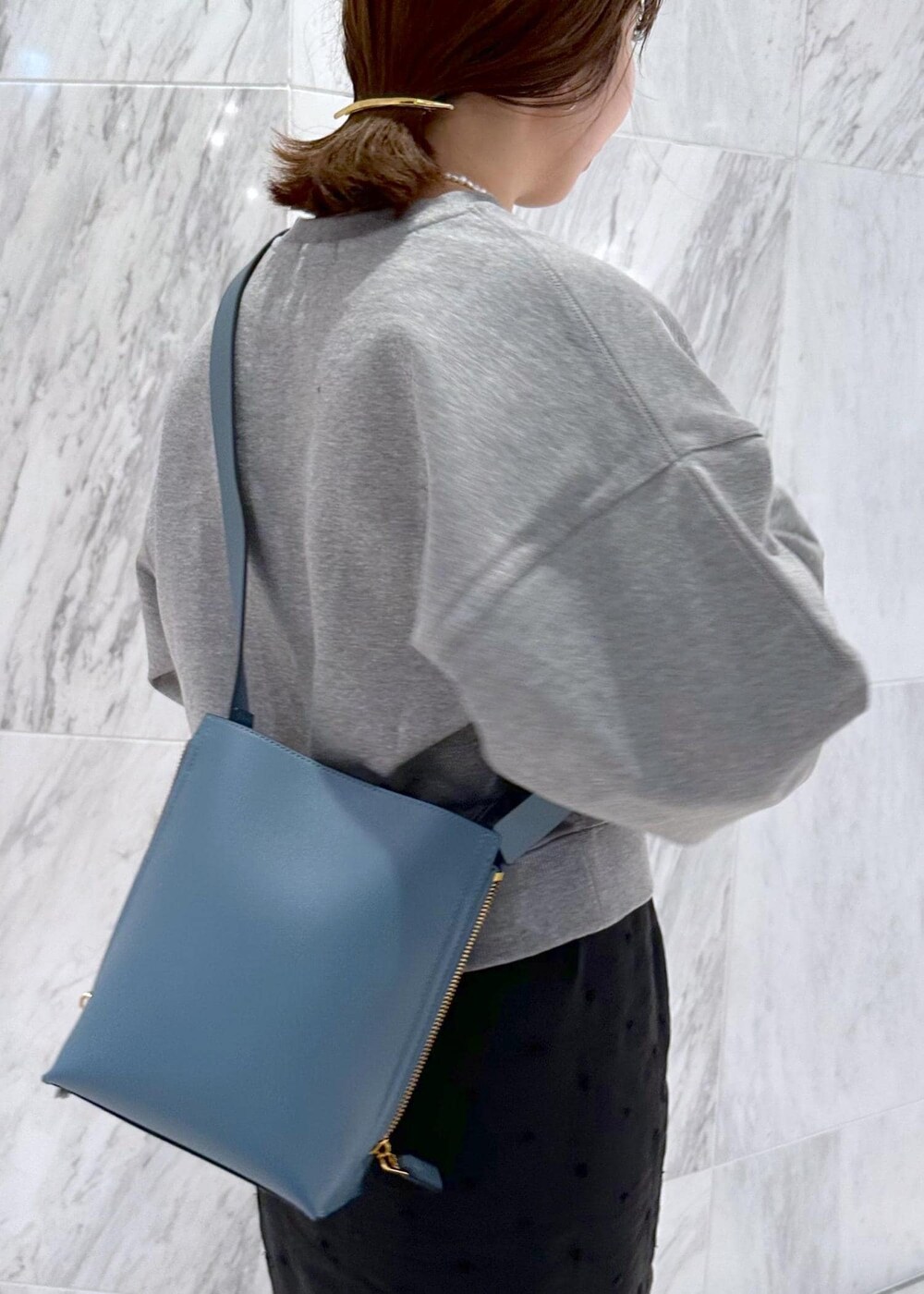 グレー系のスウェット、ブルー系のショルダーバッグ、ブラック系のスカートを着用したレディースの秋コーディネートの7枚目の写真