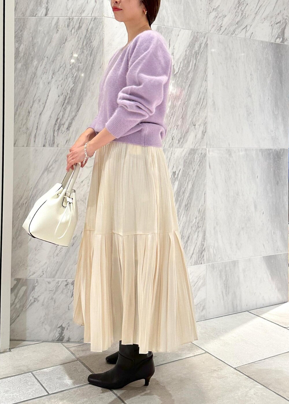 ホワイト系のハンドバッグ、ブラウン系のブーツ、ホワイト系のスカートを着用したレディースの冬コーディネートの6枚目の写真