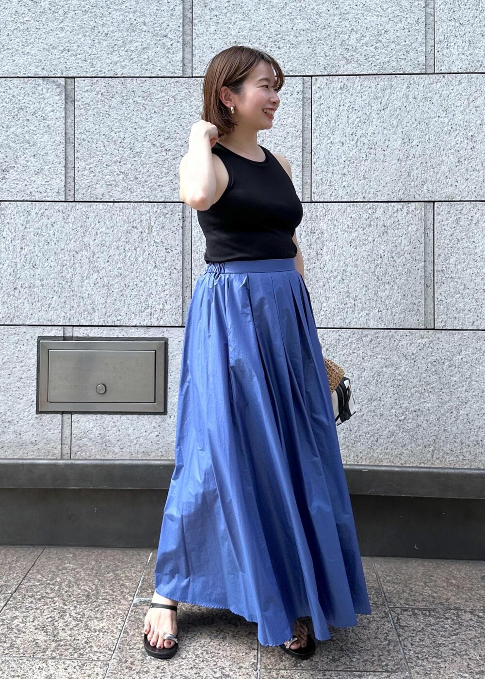 ブラック系のサンダル、ブルー系のスカート、ブラック系のタンクトップを着用したレディースの夏コーディネートの3枚目の写真