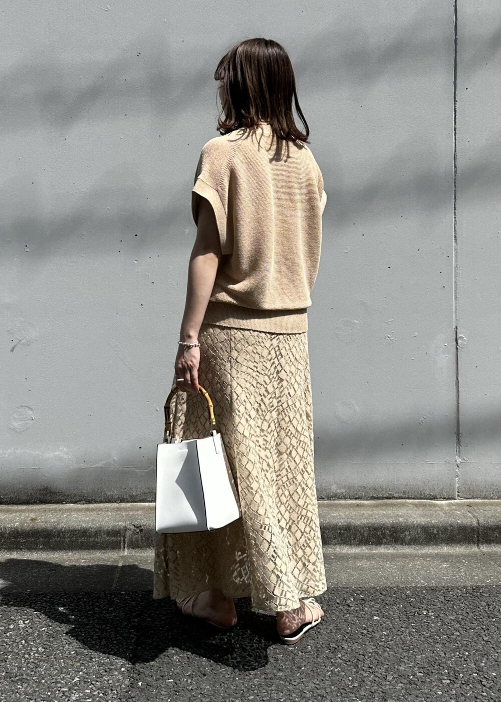 ベージュ系のスカート、ホワイト系のハンドバッグ、ホワイト系のサンダルを着用したレディースの春コーディネートの3枚目の写真