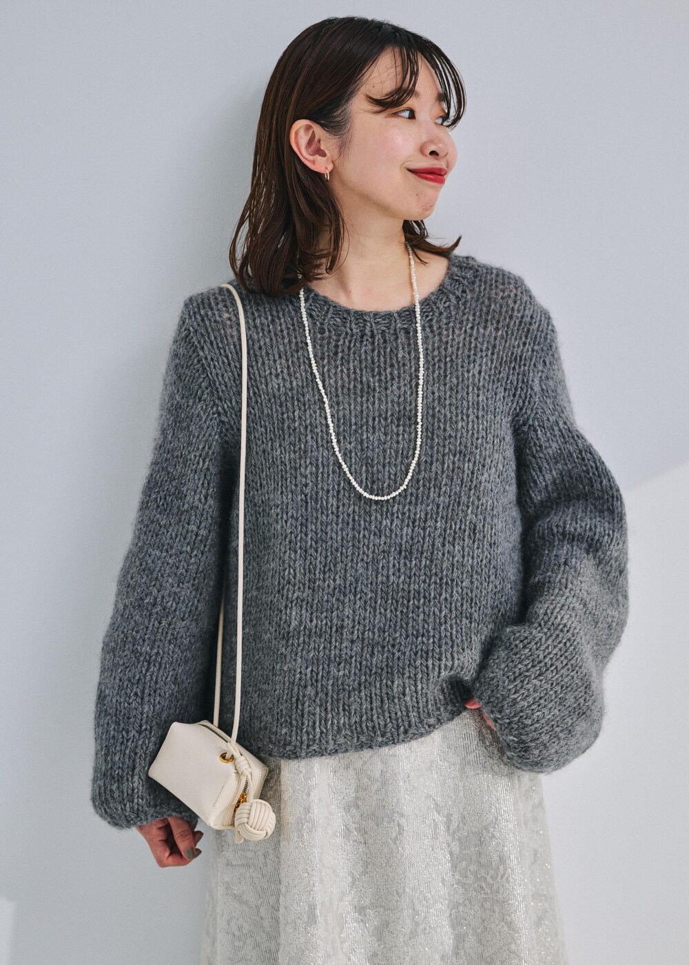 ホワイト系のショルダーバッグ、グレー系のニット/セーター、ホワイト系のワンピースを着用したレディースの冬コーディネートの3枚目の写真