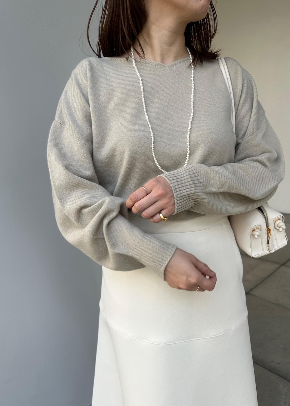 ホワイト系のハンドバッグ、ホワイト系のスカート、ベージュ系のニット/セーターを着用したレディースの冬コーディネートの5枚目の写真