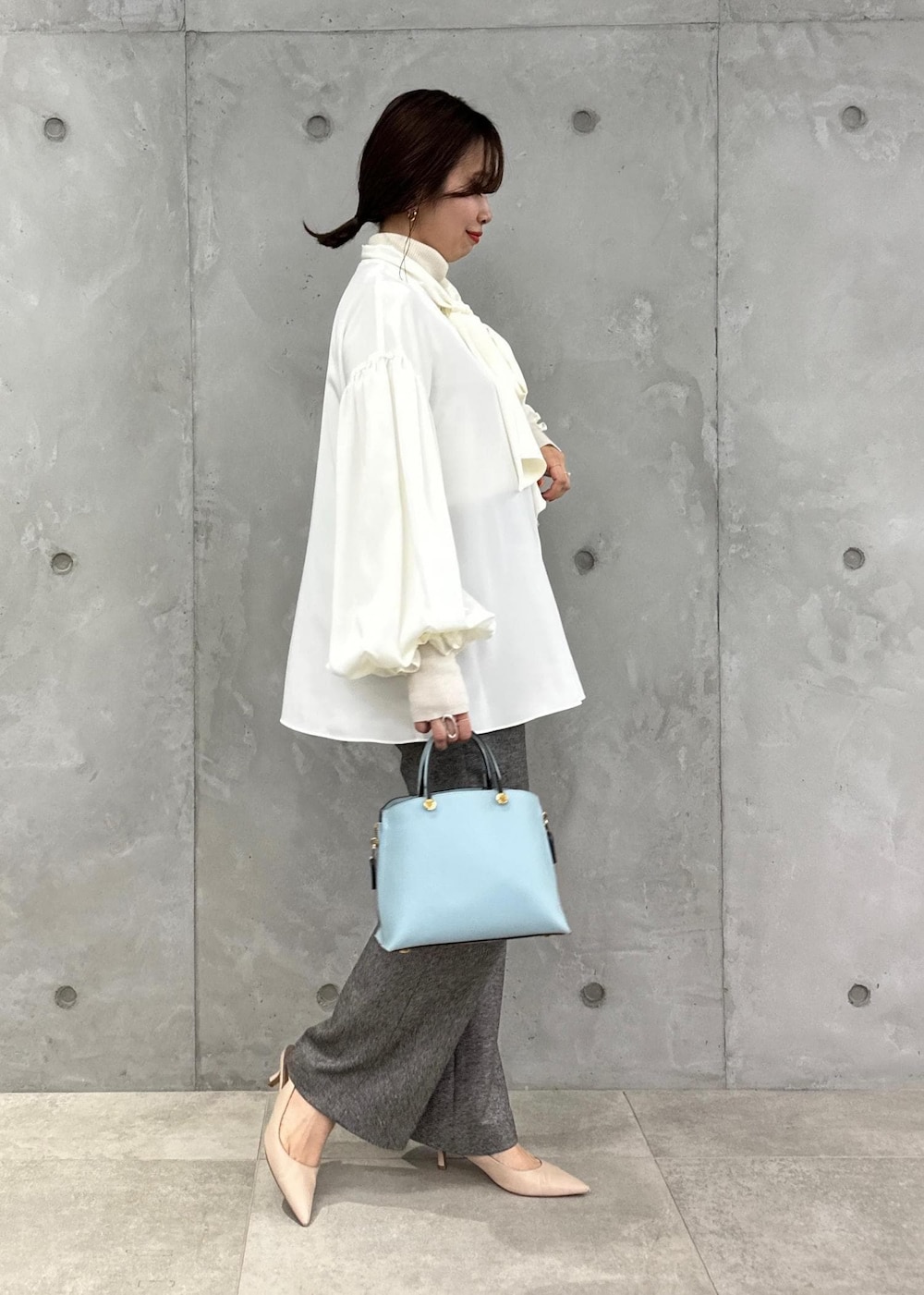 ブルー系のハンドバッグ、ベージュ系のパンプス、グレー系のその他パンツを着用したレディースの秋コーディネートの3枚目の写真