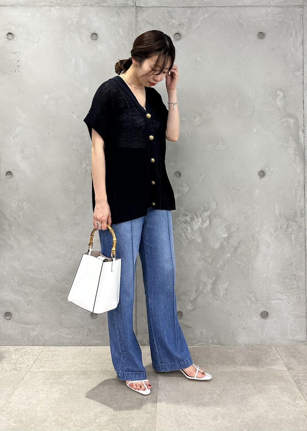ブルー系のベスト、ブルー系のデニムパンツ、ホワイト系のサンダルを着用したレディースの春コーディネートの2枚目の写真