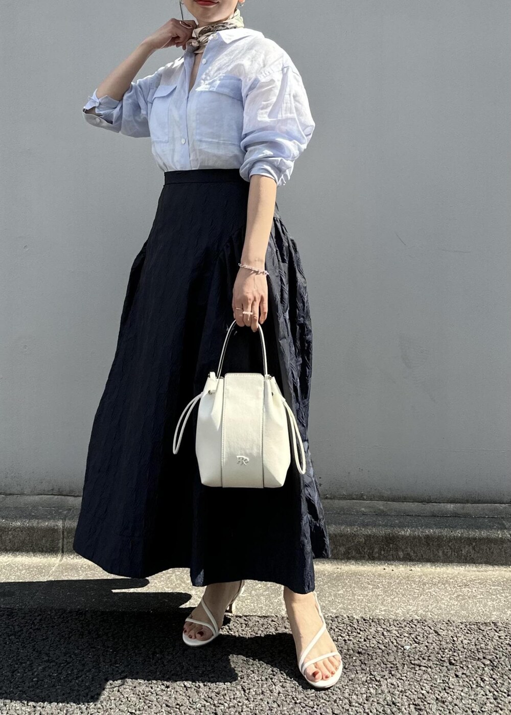 ブルー系のスカート、ブルー系のシャツ/ブラウス、ホワイト系のハンドバッグを着用したレディースの春コーディネートの9枚目の写真