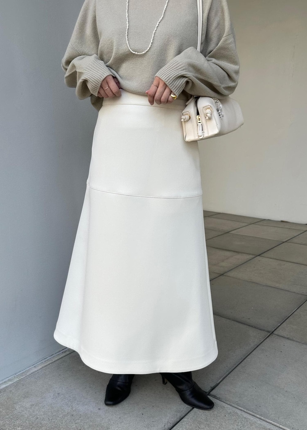 ホワイト系のハンドバッグ、ホワイト系のスカート、ベージュ系のニット/セーターを着用したレディースの冬コーディネートの4枚目の写真