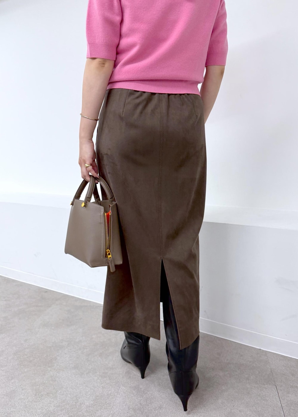 ブラック系のブーツ、ブラウン系のスカート、ブラウン系のハンドバッグを着用したレディースの秋コーディネートの6枚目の写真