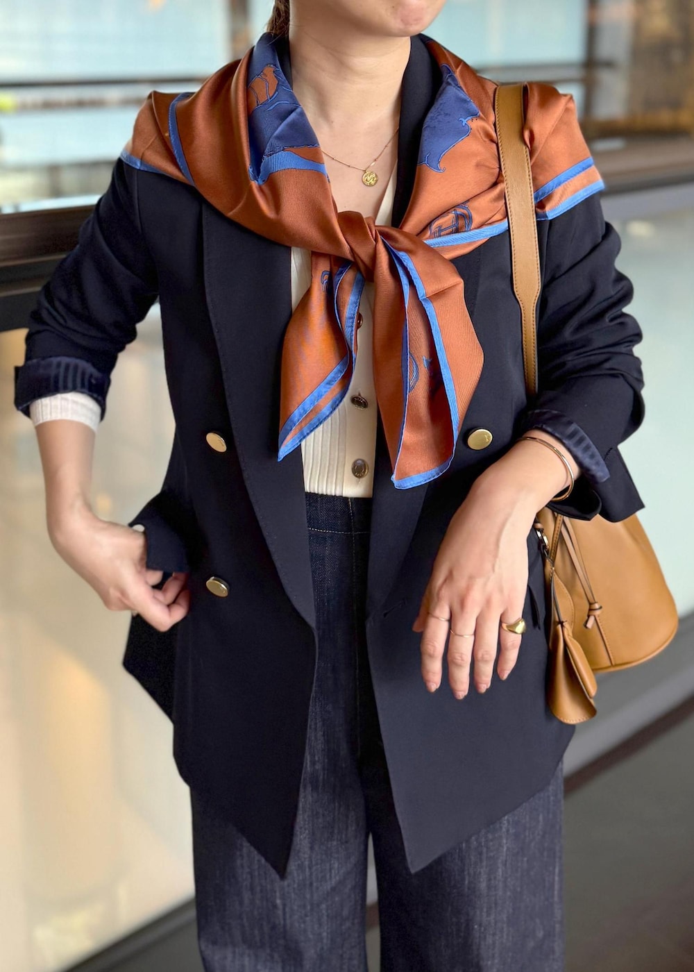 イエロー系のハンドバッグ、ブルー系のデニムパンツ、ホワイト系のカーディガン/ボレロを着用したレディースの秋コーディネートの4枚目の写真