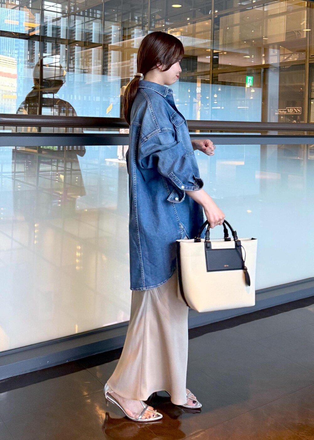 ベージュ系のスカート、ブルー系のシャツ/ブラウス、ホワイト系のトートバッグを着用したレディースの夏コーディネートの2枚目の写真