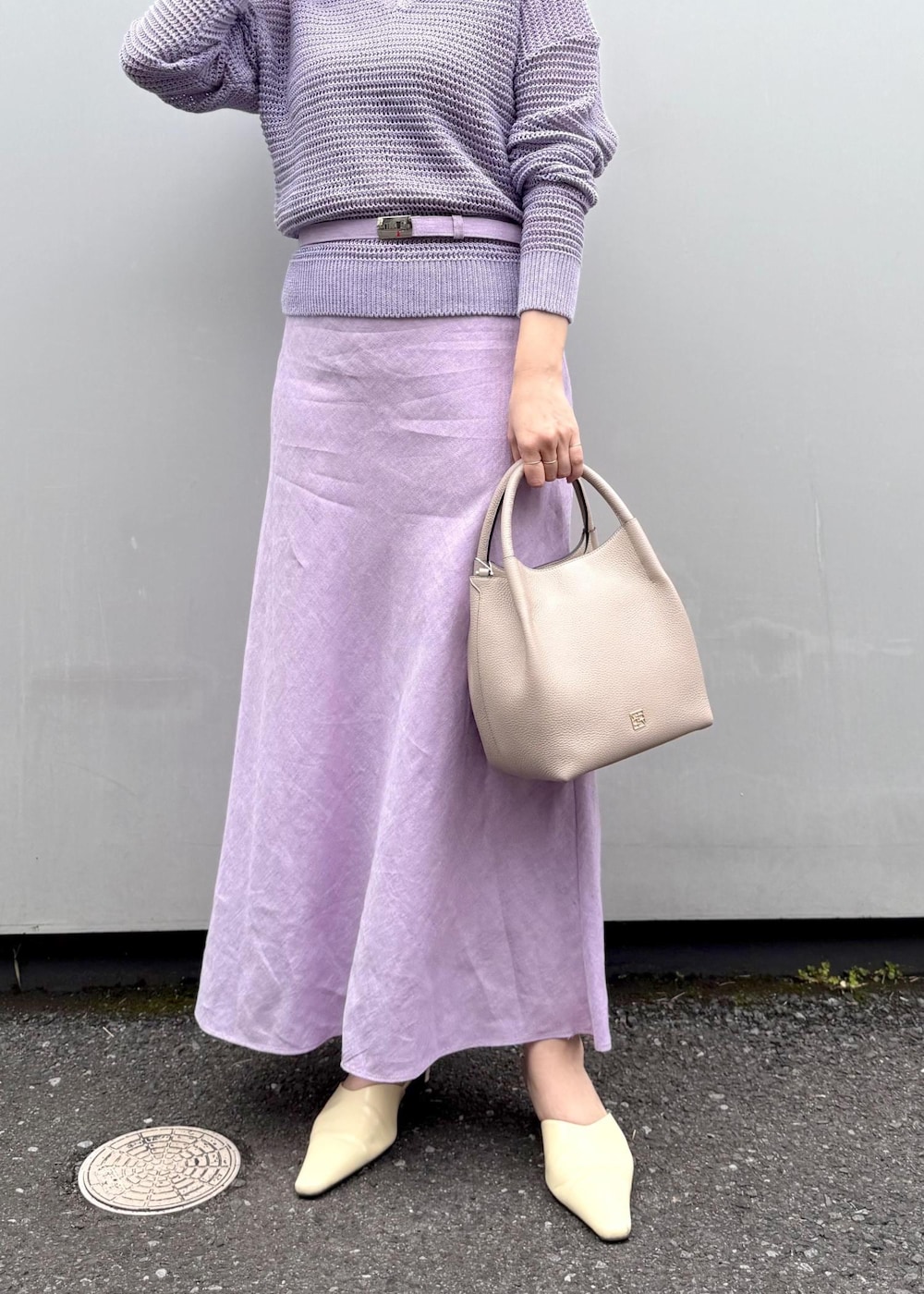 パープル系のニット/セーター、パープル系のスカート、グレー系のハンドバッグを着用したレディースの春コーディネートの5枚目の写真
