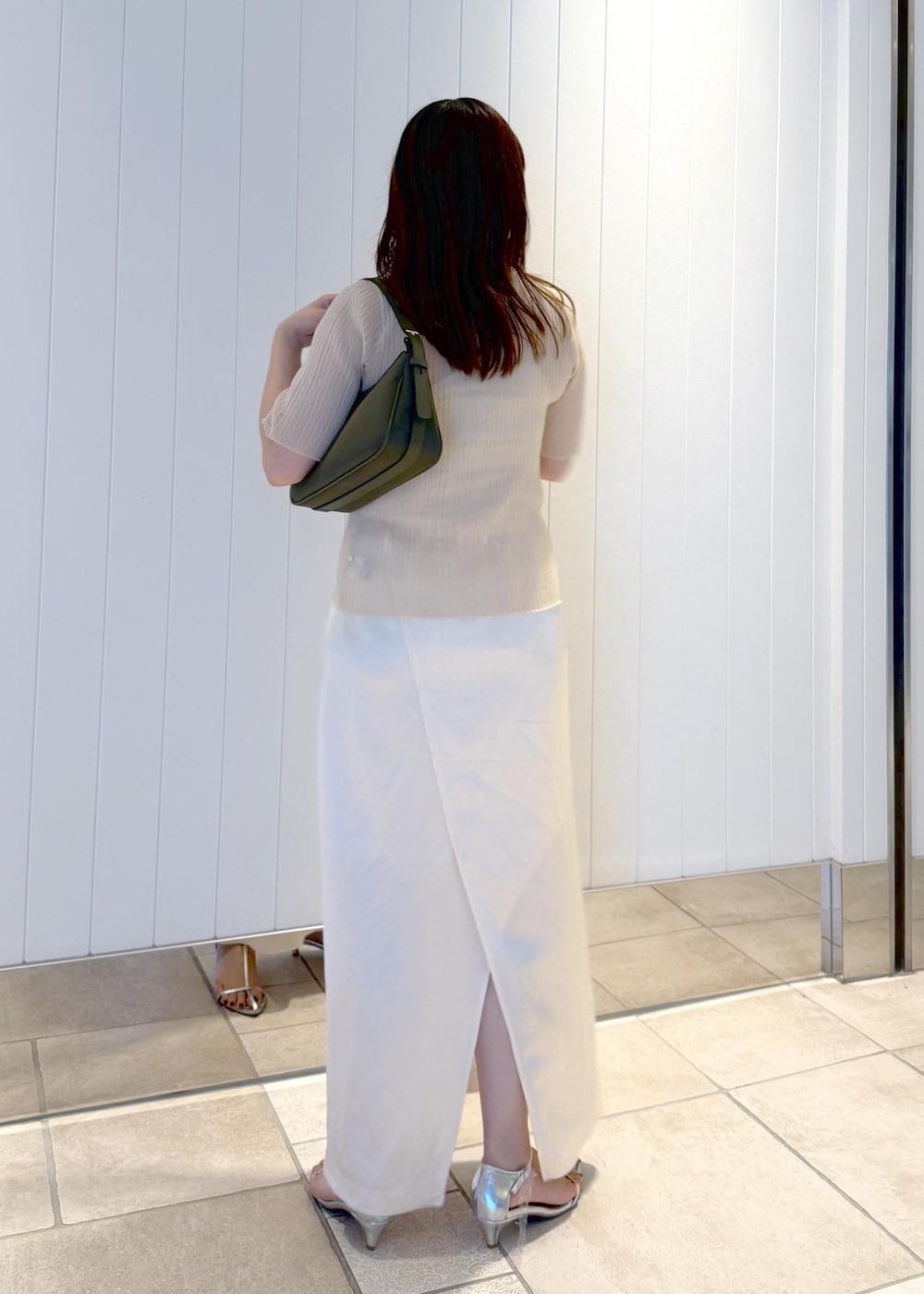 ホワイト系のスカート、ベージュ系のニット/セーター、グリーン系のハンドバッグを着用したレディースの夏コーディネートの3枚目の写真