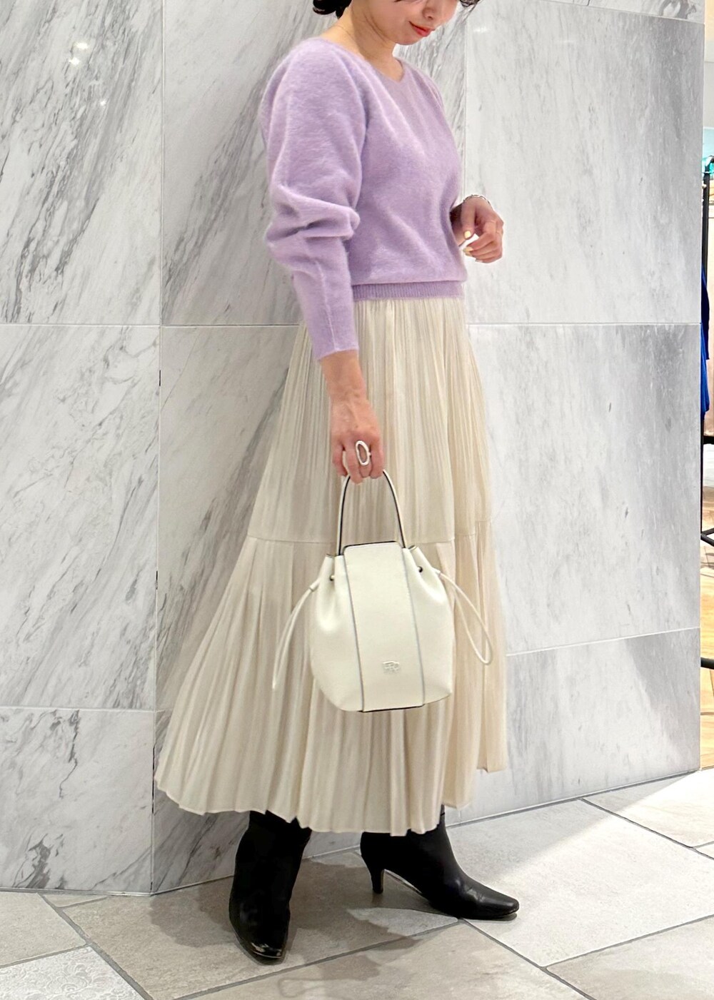 ホワイト系のハンドバッグ、ブラウン系のブーツ、ホワイト系のスカートを着用したレディースの冬コーディネートの5枚目の写真