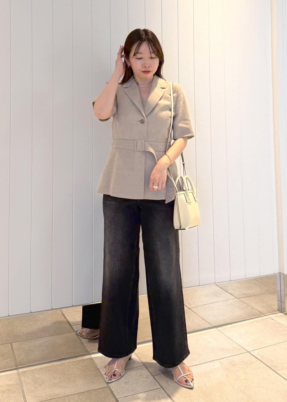 ベージュ系のテーラードジャケット、ブラック系のデニムパンツ、ホワイト系のショルダーバッグを着用したレディースの夏コーディネートの2枚目の写真