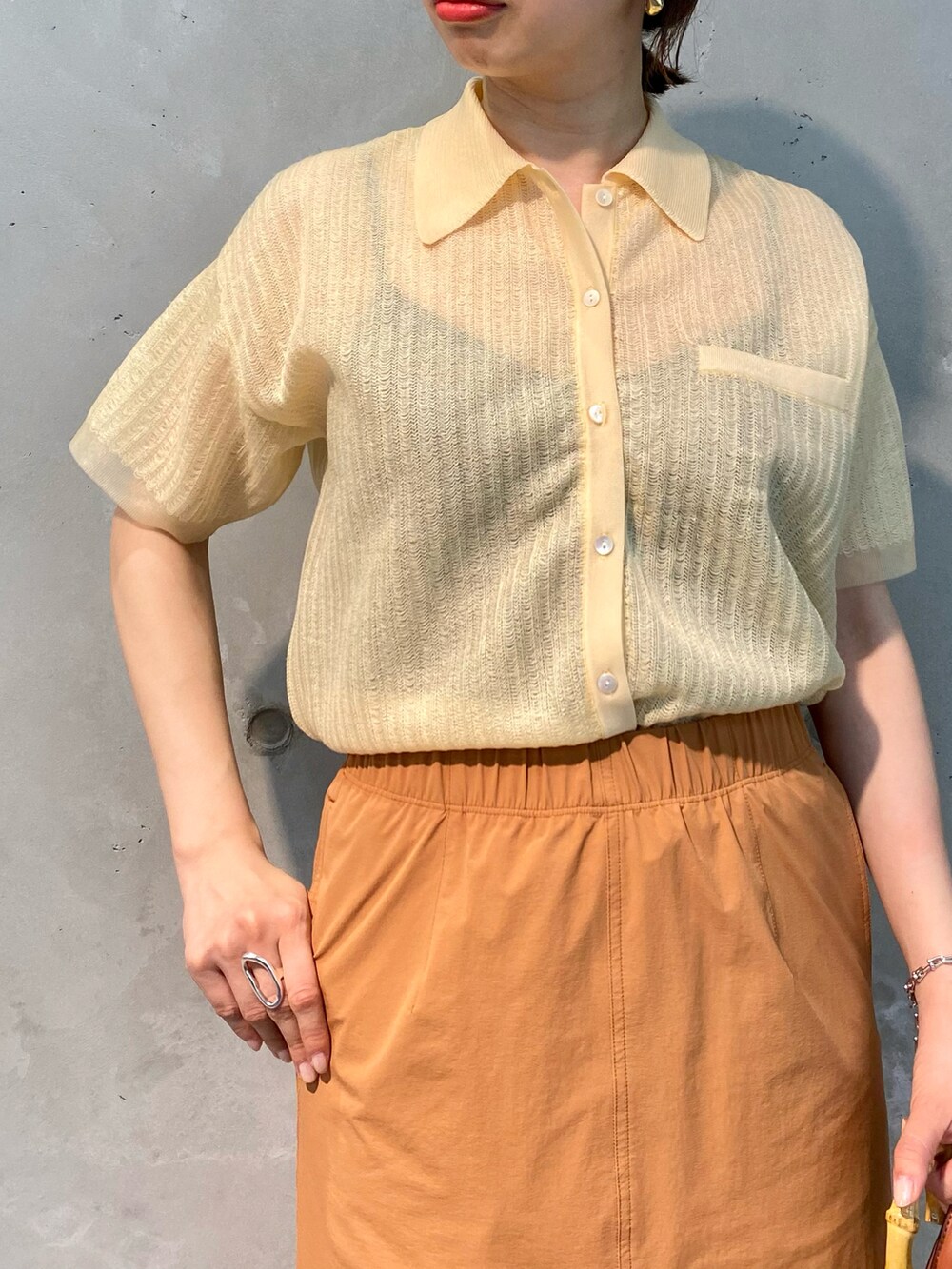 ベージュ系のニット/セーター、オレンジ系のスカート、ブラウン系のショルダーバッグを着用したレディースの春コーディネートの4枚目の写真