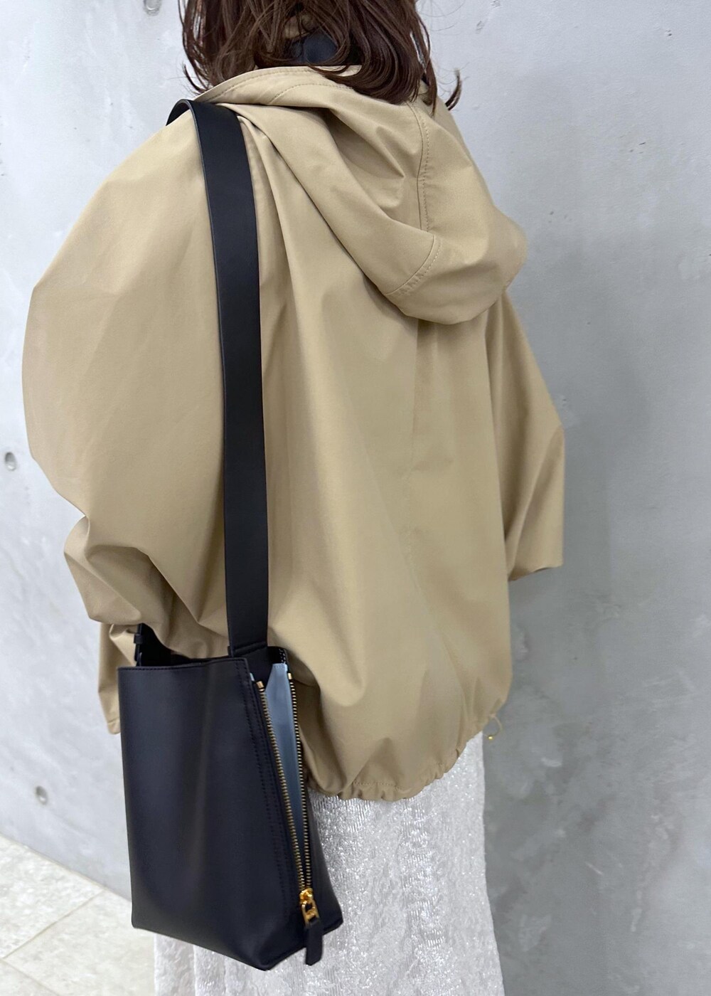 ブラック系のブーツ、ホワイト系のワンピース、ベージュ系のマウンテンパーカーを着用したレディースの秋コーディネートの7枚目の写真