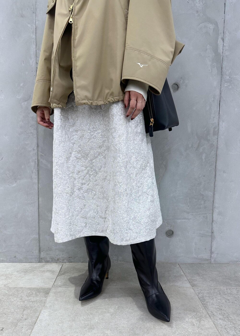 ブラック系のブーツ、ホワイト系のワンピース、ベージュ系のマウンテンパーカーを着用したレディースの秋コーディネートの8枚目の写真