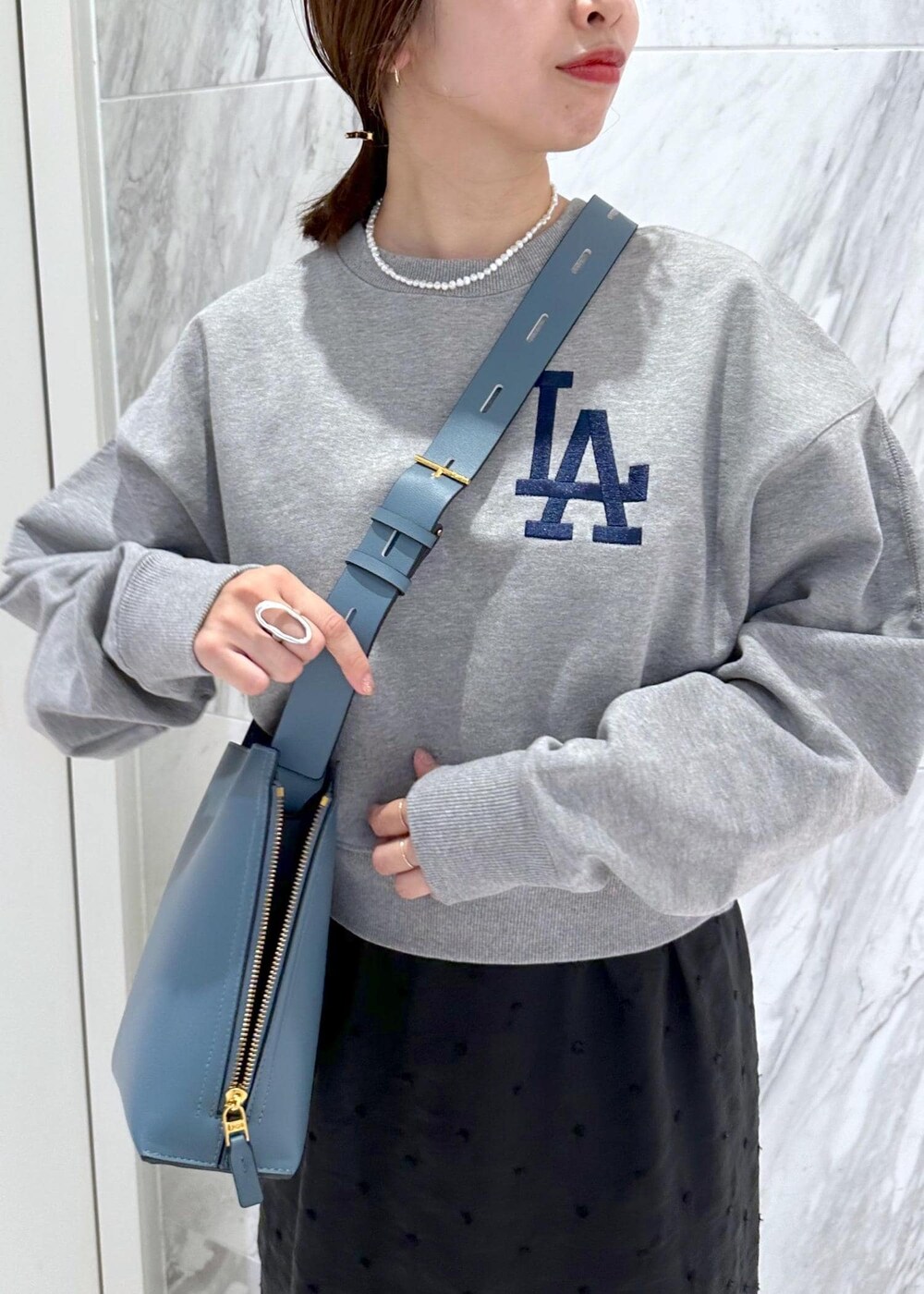 グレー系のスウェット、ブルー系のショルダーバッグ、ブラック系のスカートを着用したレディースの秋コーディネートの6枚目の写真