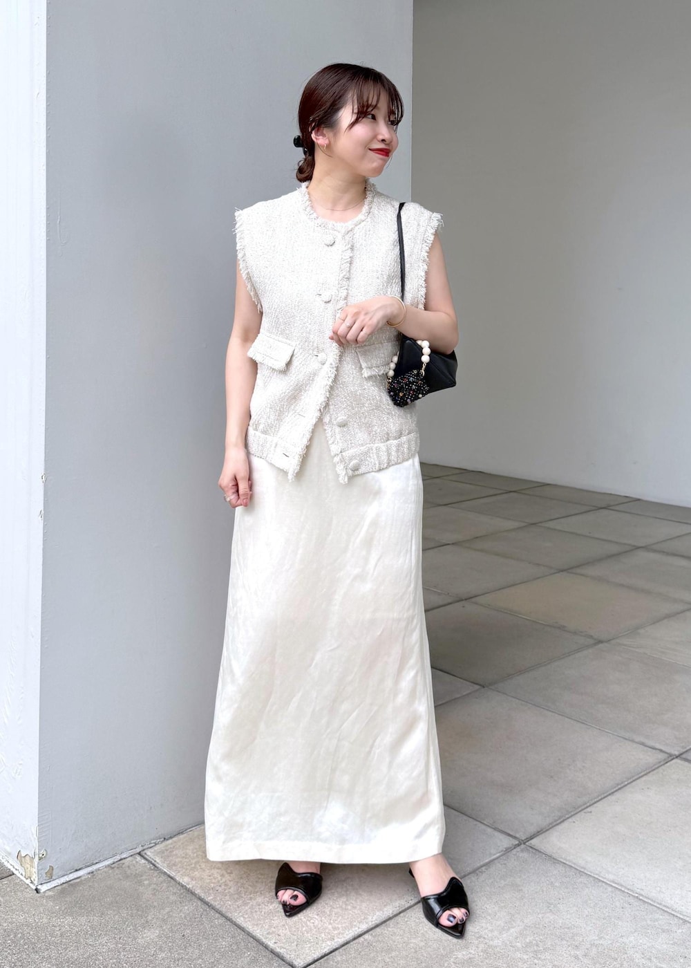 ホワイト系のスカート、ホワイト系のベストを着用したレディースの夏コーディネートの2枚目の写真