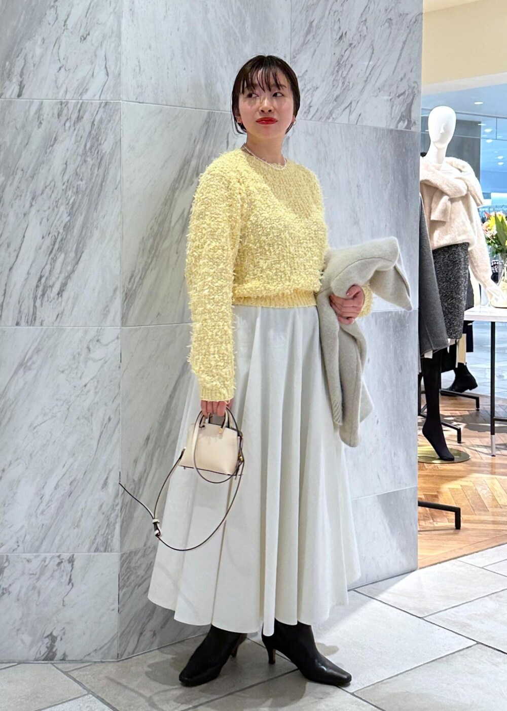ベージュ系のショルダーバッグ、ホワイト系のカーディガン/ボレロ、ホワイト系のスカートを着用したレディースの冬コーディネートの6枚目の写真