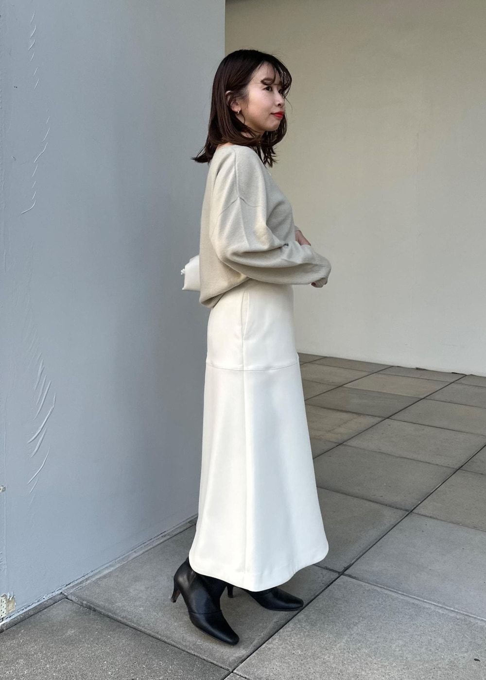 ホワイト系のハンドバッグ、ホワイト系のスカート、ベージュ系のニット/セーターを着用したレディースの冬コーディネートの2枚目の写真