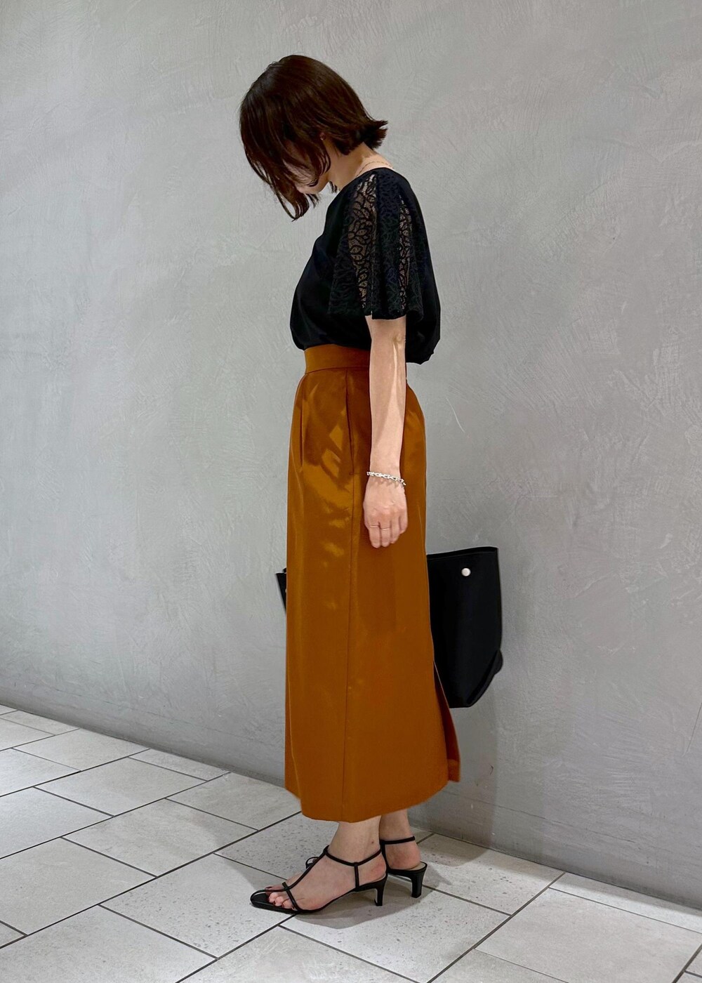 ブラック系のハンドバッグ、ブラック系のサンダル、ブラック系のTシャツ/カットソーを着用したレディースの夏コーディネートの2枚目の写真