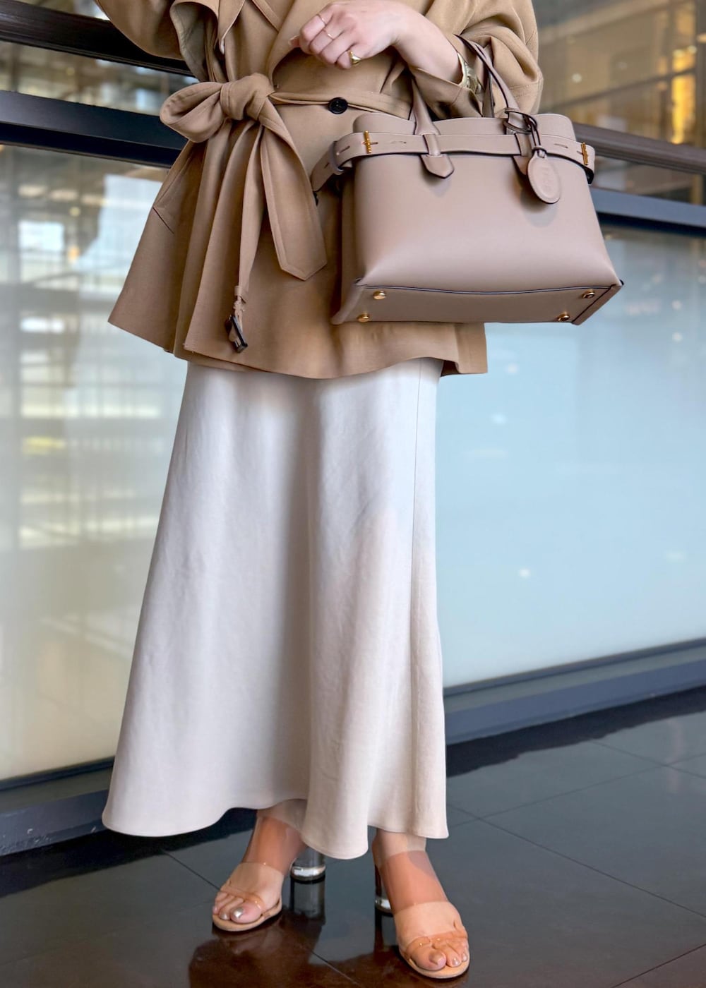 ベージュ系のトレンチコート、ベージュ系のスカート、ベージュ系のシャツ/ブラウスを着用したレディースの春コーディネートの5枚目の写真