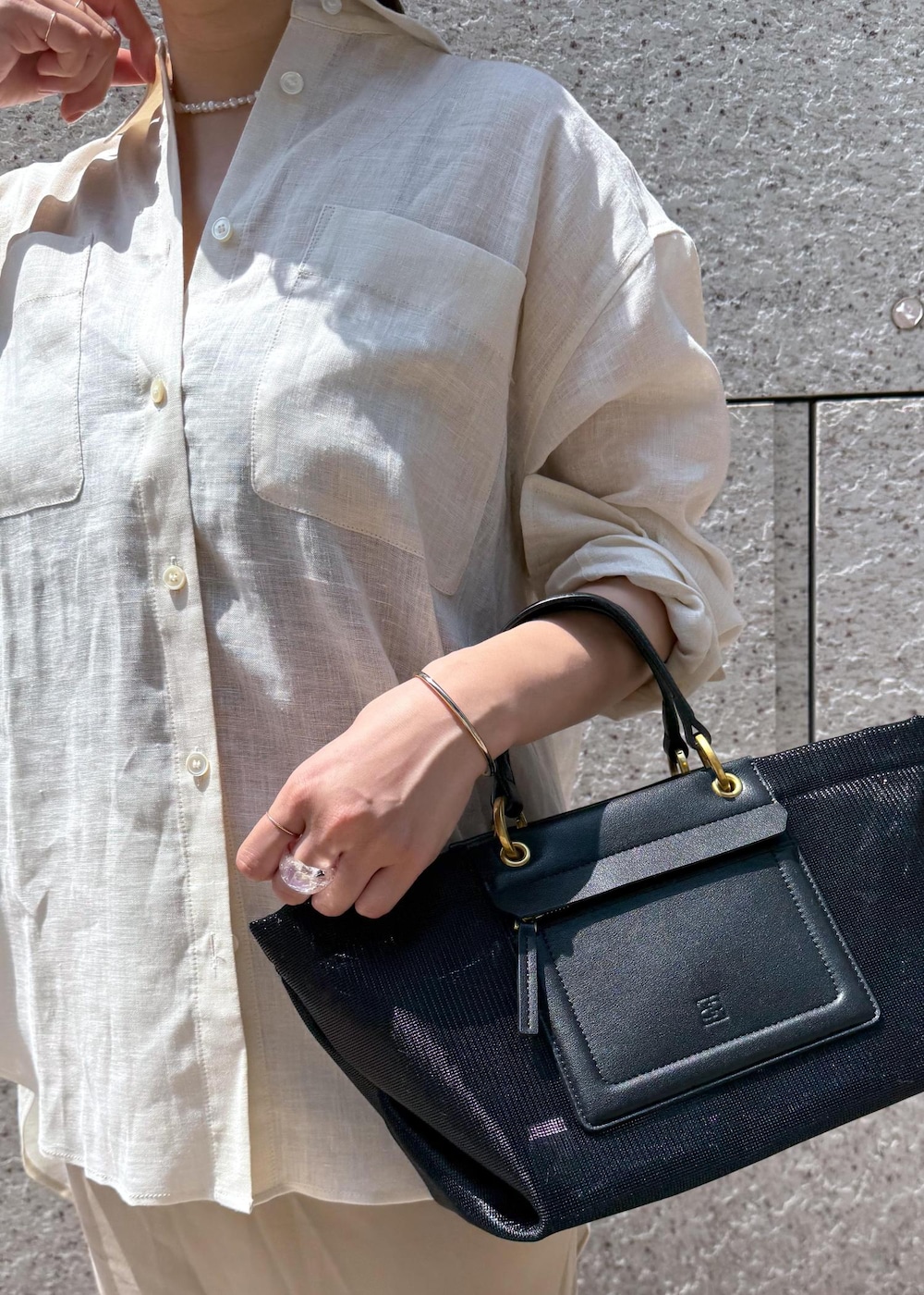 ブラック系のハンドバッグ、ベージュ系のスカート、ホワイト系のシャツ/ブラウスを着用したレディースの夏コーディネートの6枚目の写真