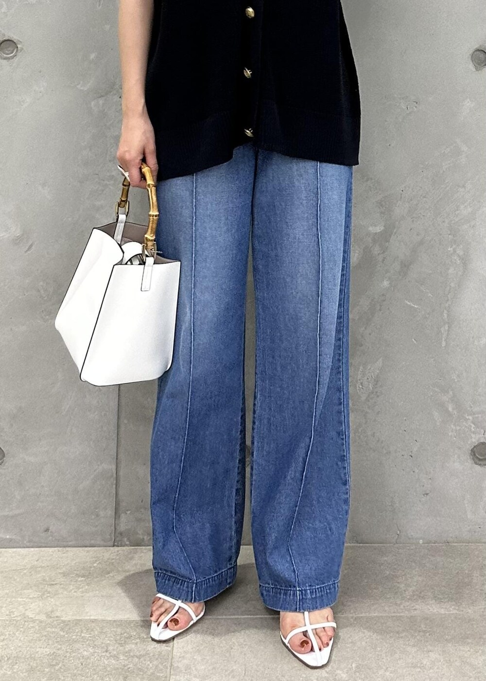 ブルー系のベスト、ブルー系のデニムパンツ、ホワイト系のサンダルを着用したレディースの春コーディネートの6枚目の写真