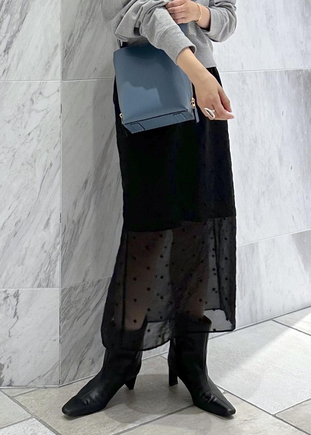グレー系のスウェット、ブルー系のショルダーバッグ、ブラック系のスカートを着用したレディースの秋コーディネートの9枚目の写真