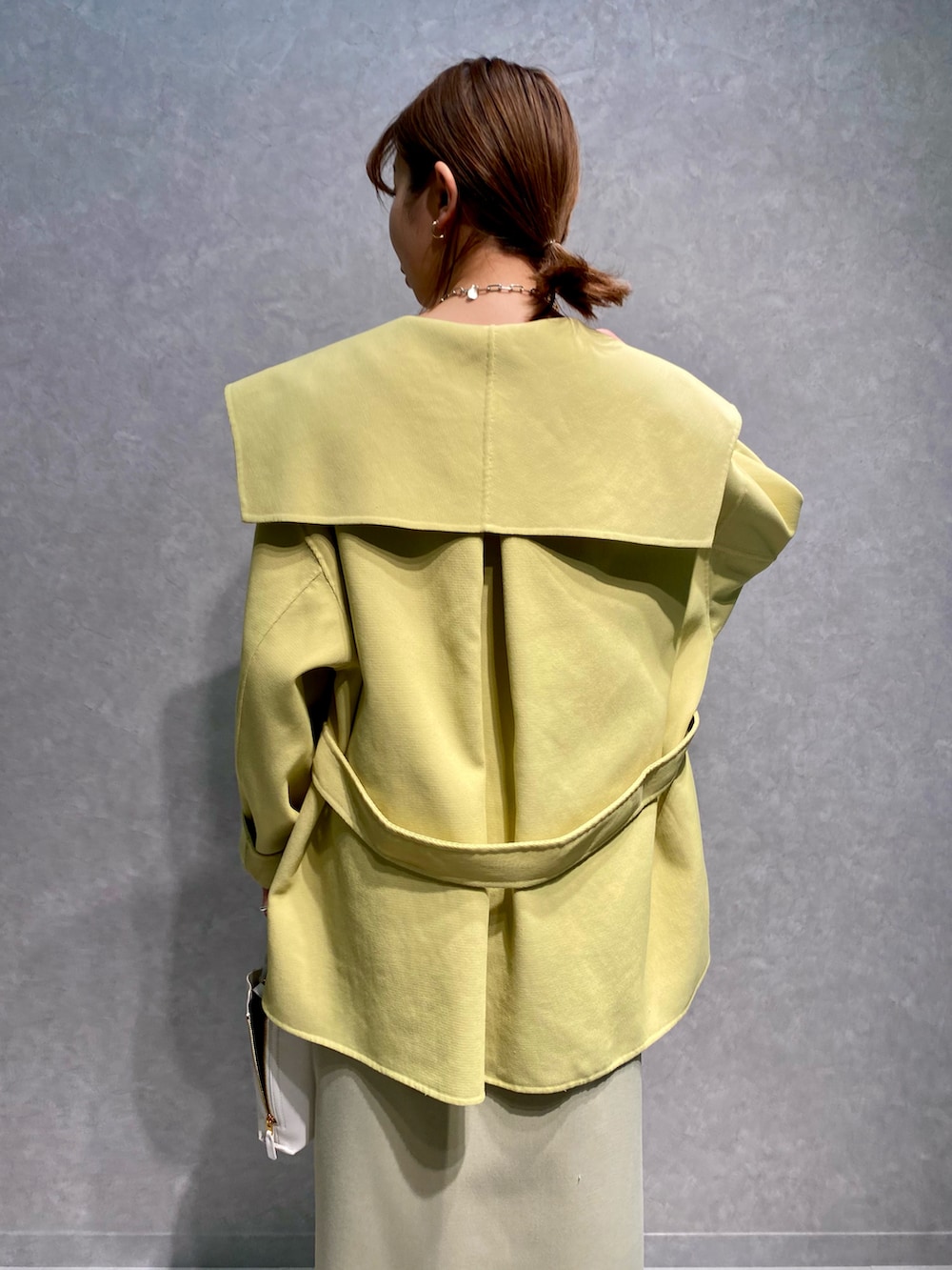 ブルー系のTシャツ/カットソー、イエロー系のトレンチコート、ベージュ系のスカートを着用したレディースの春コーディネートの4枚目の写真