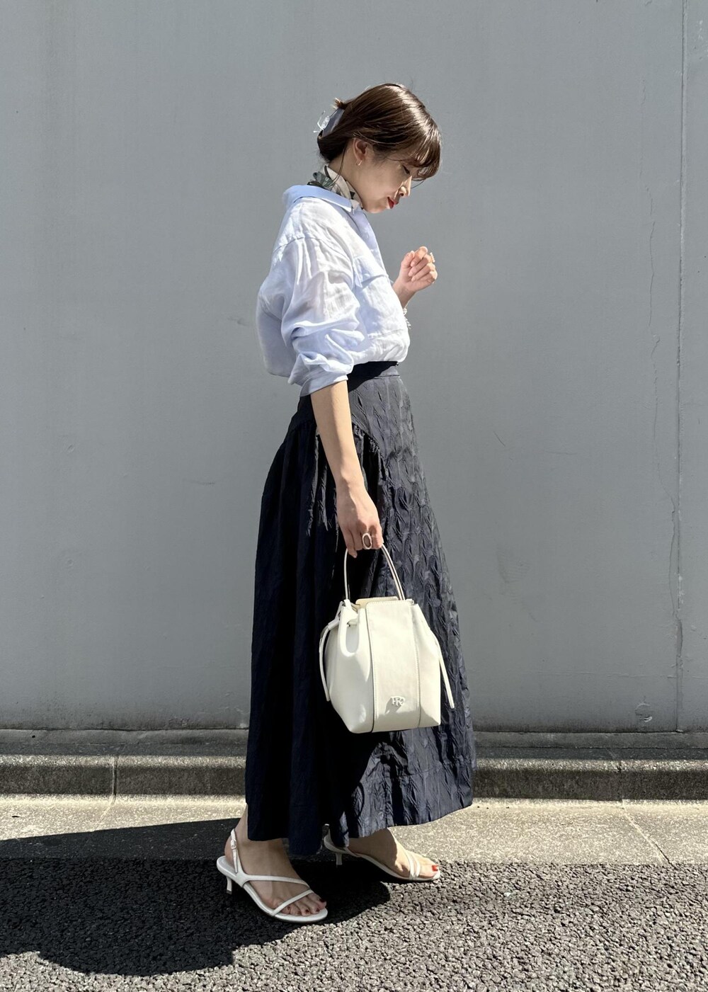 ブルー系のスカート、ブルー系のシャツ/ブラウス、ホワイト系のハンドバッグを着用したレディースの春コーディネートの3枚目の写真
