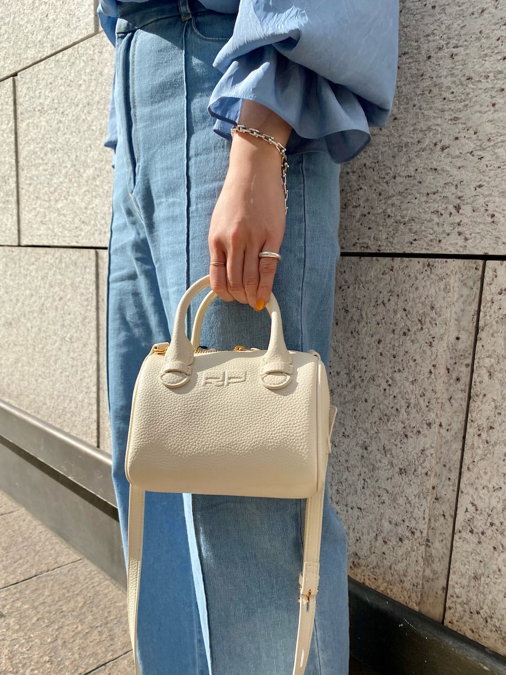 ブルー系のシャツ/ブラウス、ホワイト系のハンドバッグ、ブルー系のデニムパンツを着用したレディースの春コーディネートの5枚目の写真