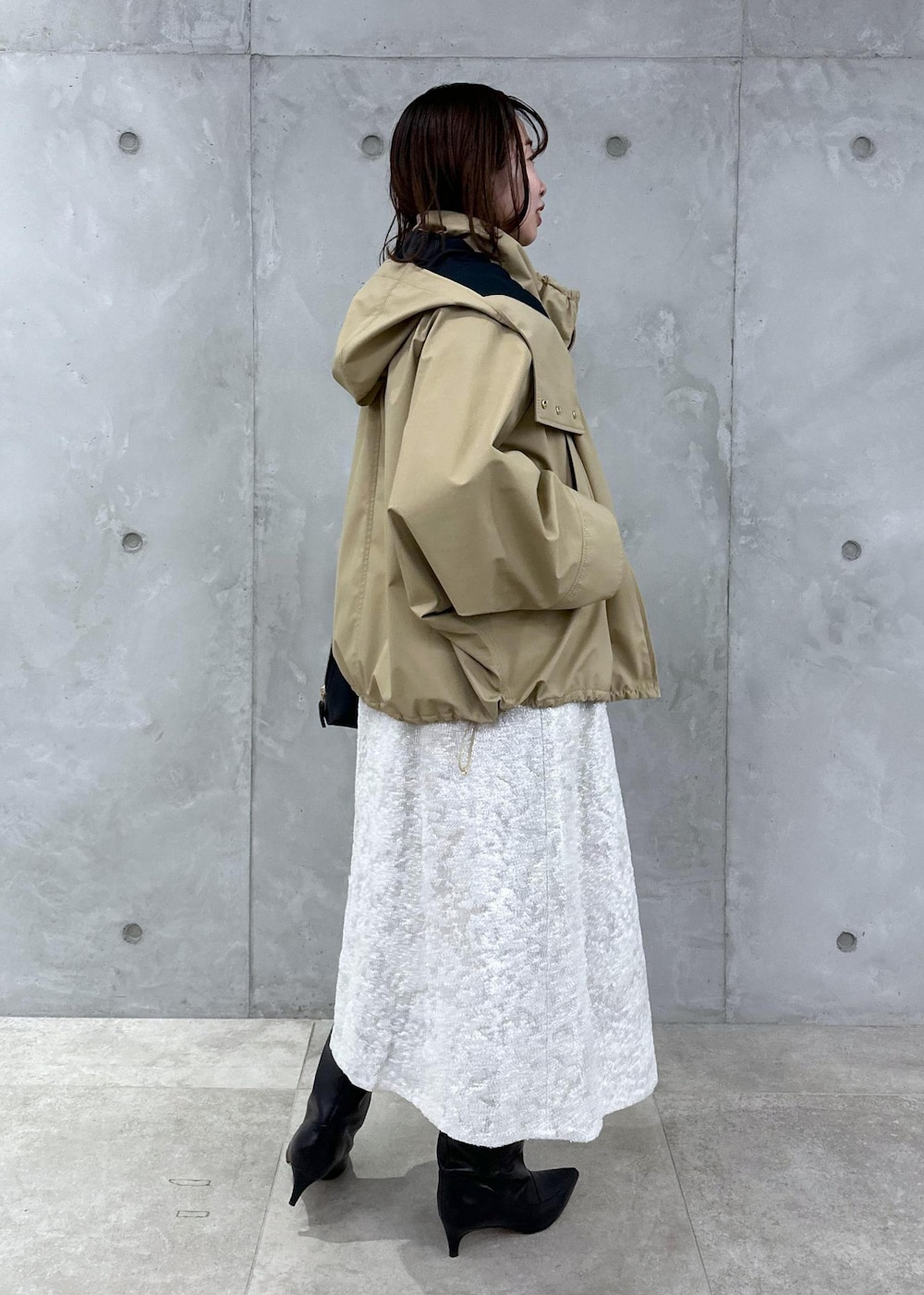 ブラック系のブーツ、ホワイト系のワンピース、ベージュ系のマウンテンパーカーを着用したレディースの秋コーディネートの2枚目の写真