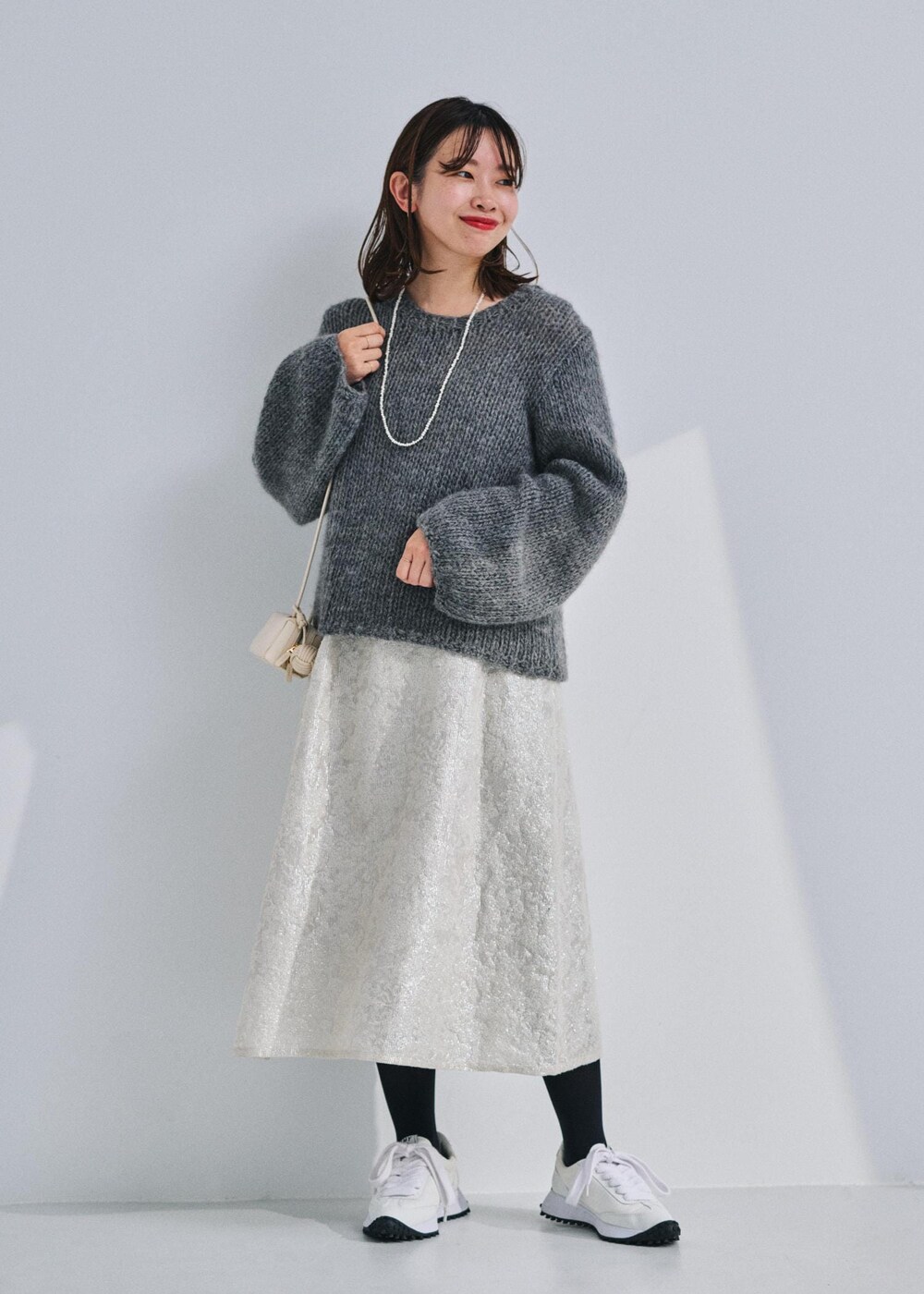 ホワイト系のショルダーバッグ、グレー系のニット/セーター、ホワイト系のワンピースを着用したレディースの冬コーディネートの2枚目の写真