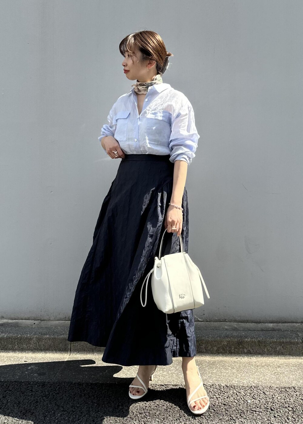 ブルー系のスカート、ブルー系のシャツ/ブラウス、ホワイト系のハンドバッグを着用したレディースの春コーディネートの2枚目の写真
