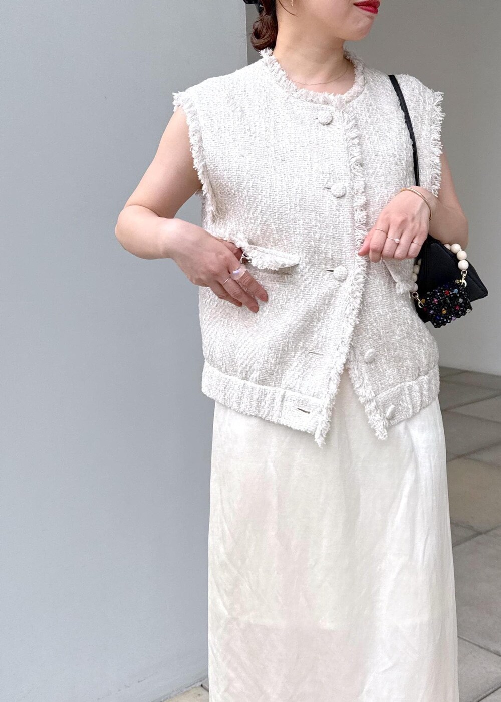 ホワイト系のスカート、ホワイト系のベストを着用したレディースの夏コーディネートの7枚目の写真