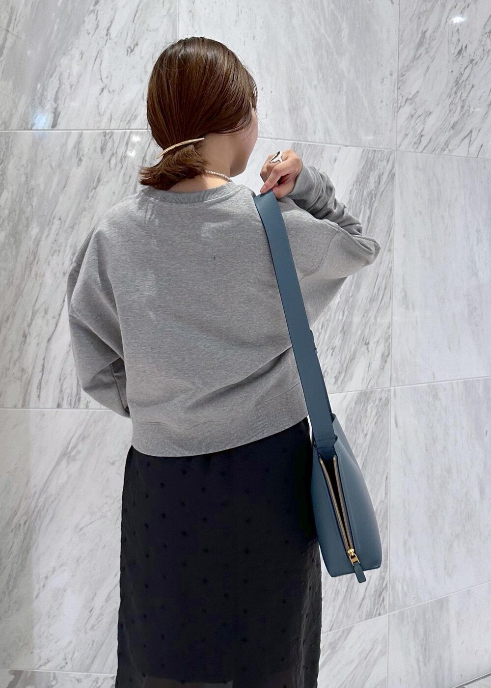 グレー系のスウェット、ブルー系のショルダーバッグ、ブラック系のスカートを着用したレディースの秋コーディネートの8枚目の写真
