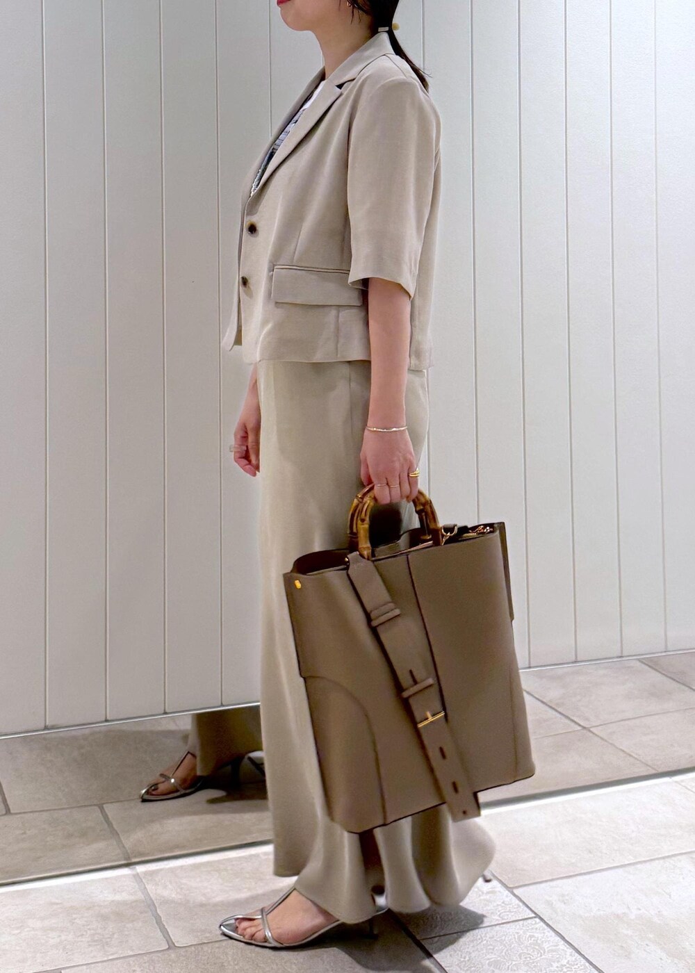 ベージュ系のトートバッグ、ホワイト系のTシャツ/カットソー、ベージュ系のスカートを着用したレディースの春コーディネートの3枚目の写真