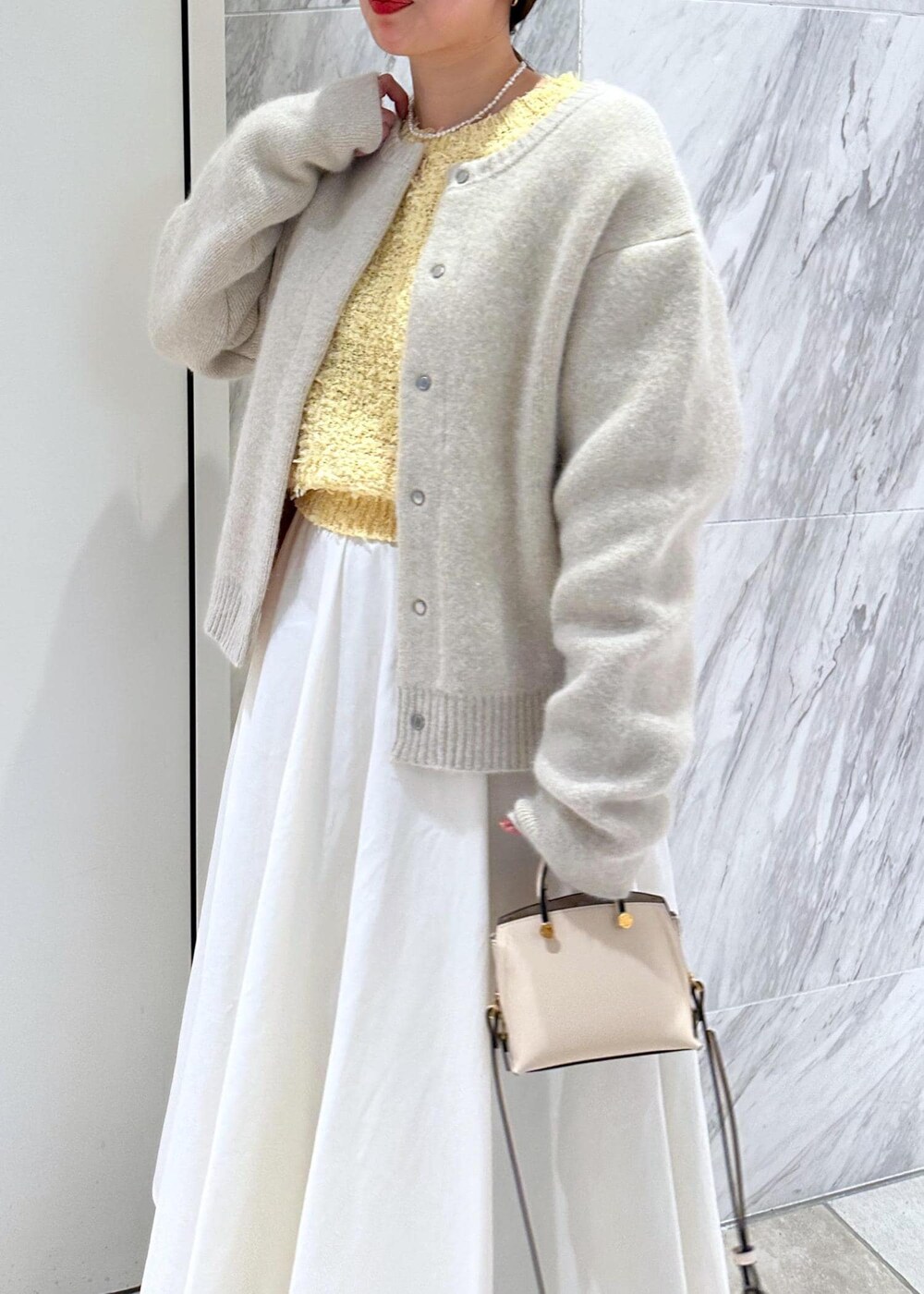 ベージュ系のショルダーバッグ、ホワイト系のカーディガン/ボレロ、ホワイト系のスカートを着用したレディースの冬コーディネートの5枚目の写真