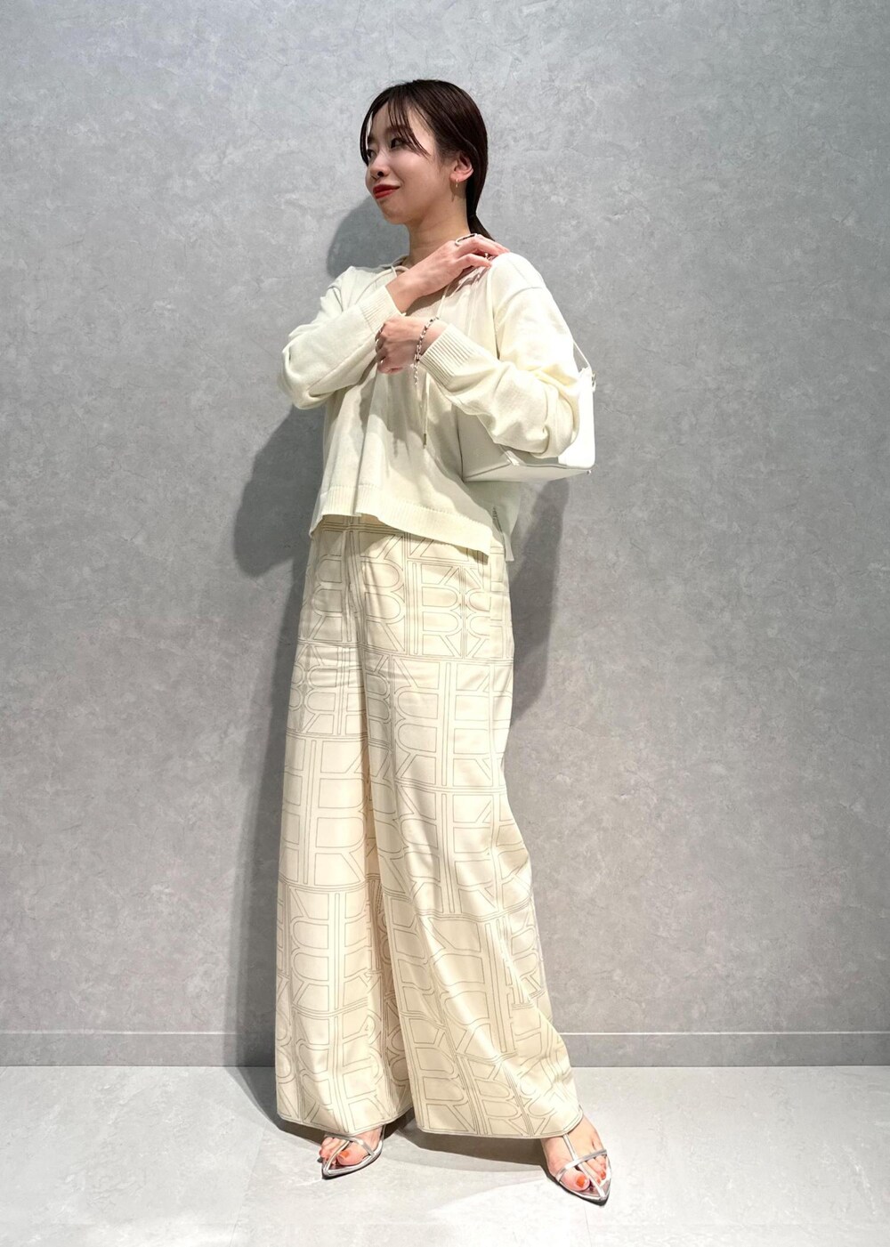 ホワイト系のニット/セーター、ホワイト系のその他パンツ、ホワイト系のハンドバッグを着用したレディースの春コーディネートの2枚目の写真