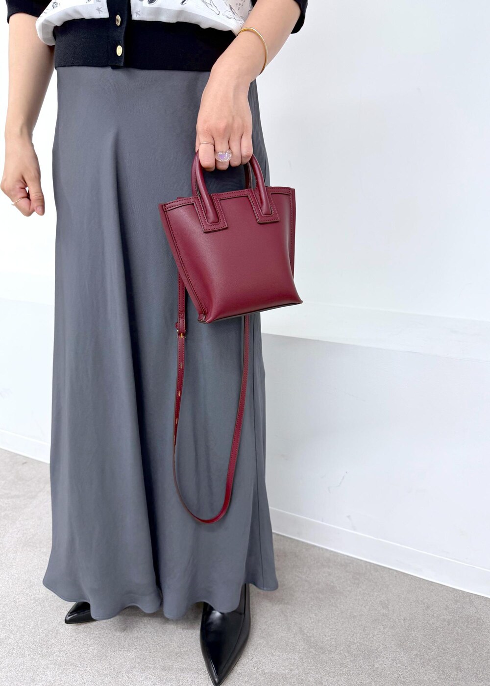 グレー系のスカート、ブラック系のシャツ/ブラウス、レッド系のショルダーバッグを着用したレディースの夏コーディネートの6枚目の写真