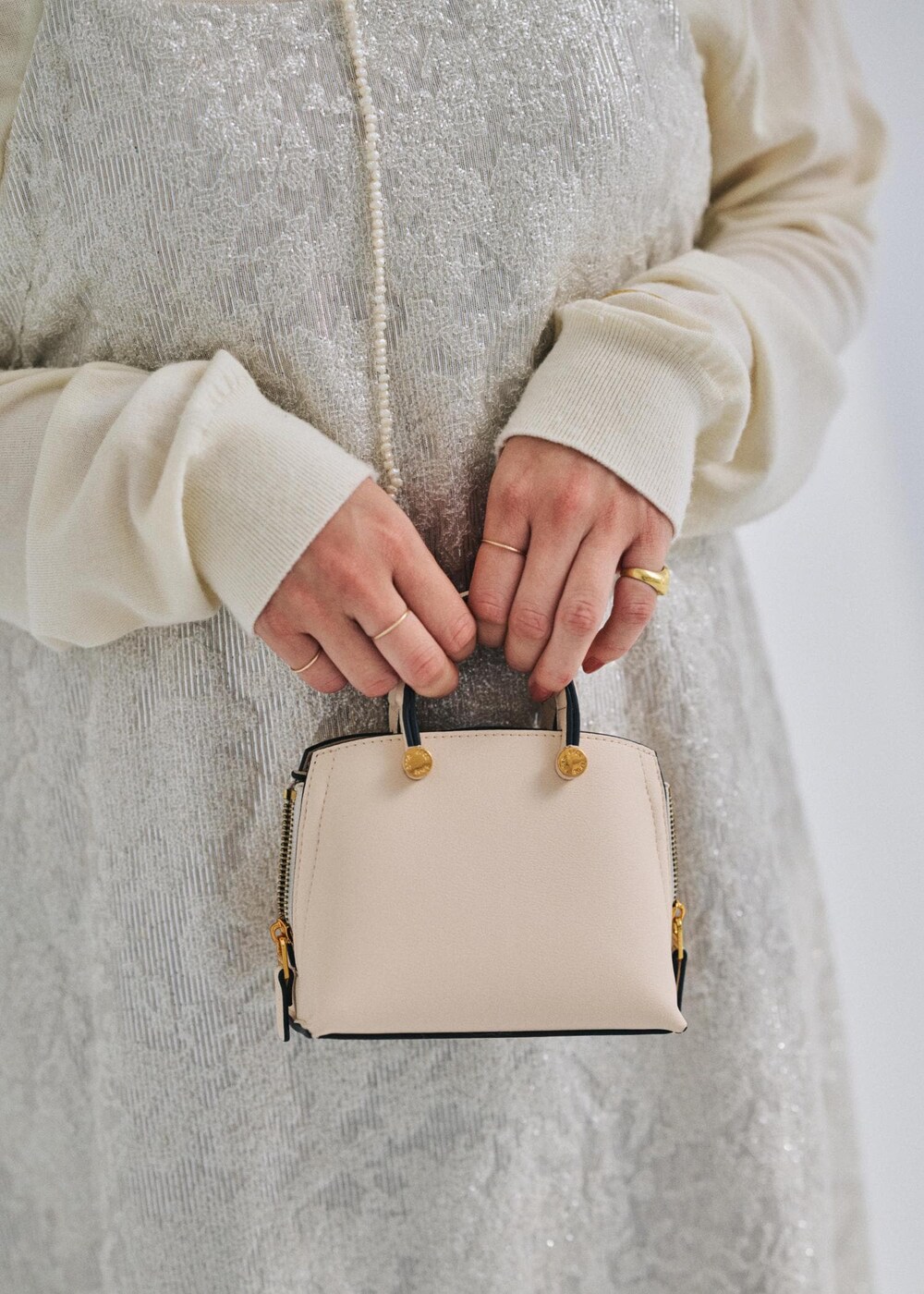 ベージュ系のショルダーバッグ、ブラック系のブーツ、ホワイト系のテーラードジャケットを着用したレディースの冬コーディネートの6枚目の写真