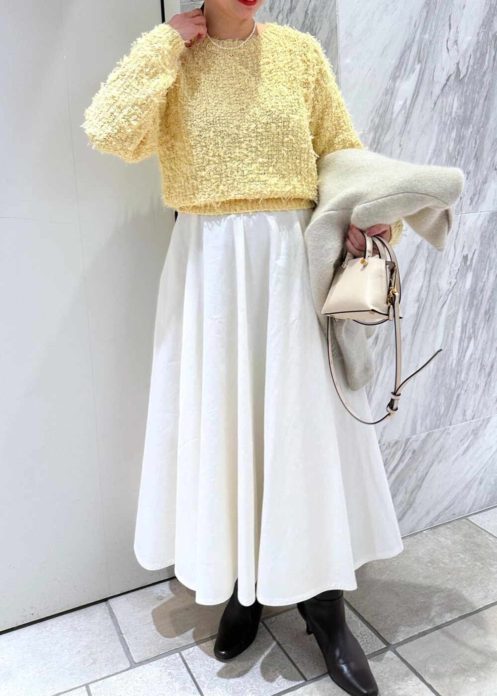 ベージュ系のショルダーバッグ、ホワイト系のカーディガン/ボレロ、ホワイト系のスカートを着用したレディースの冬コーディネートの8枚目の写真