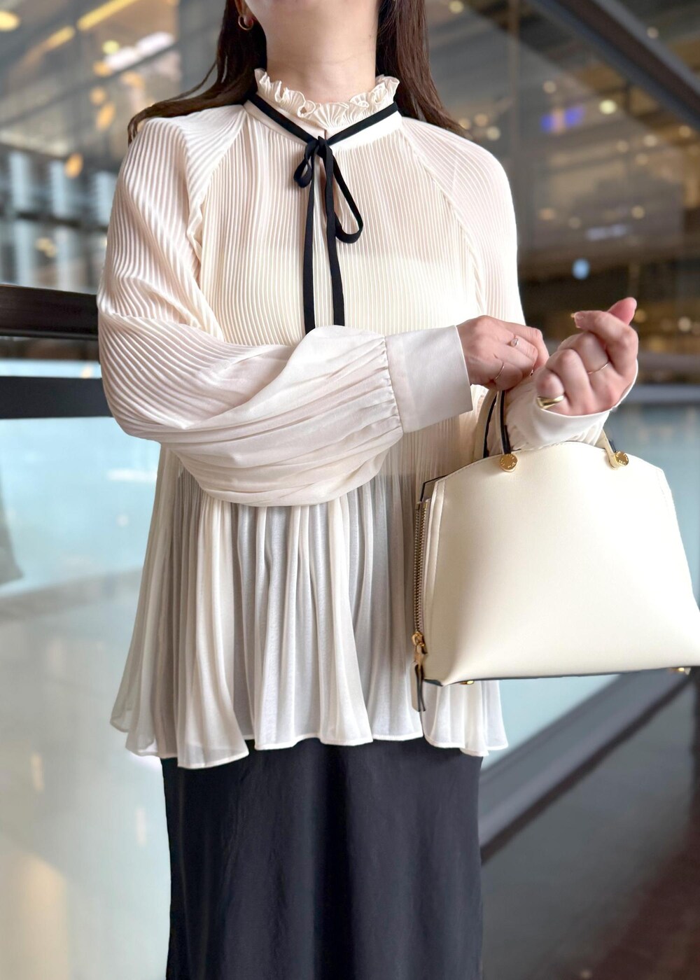 ホワイト系のハンドバッグ、ブラック系のスカート、ホワイト系のシャツ/ブラウスを着用したレディースの秋コーディネートの9枚目の写真