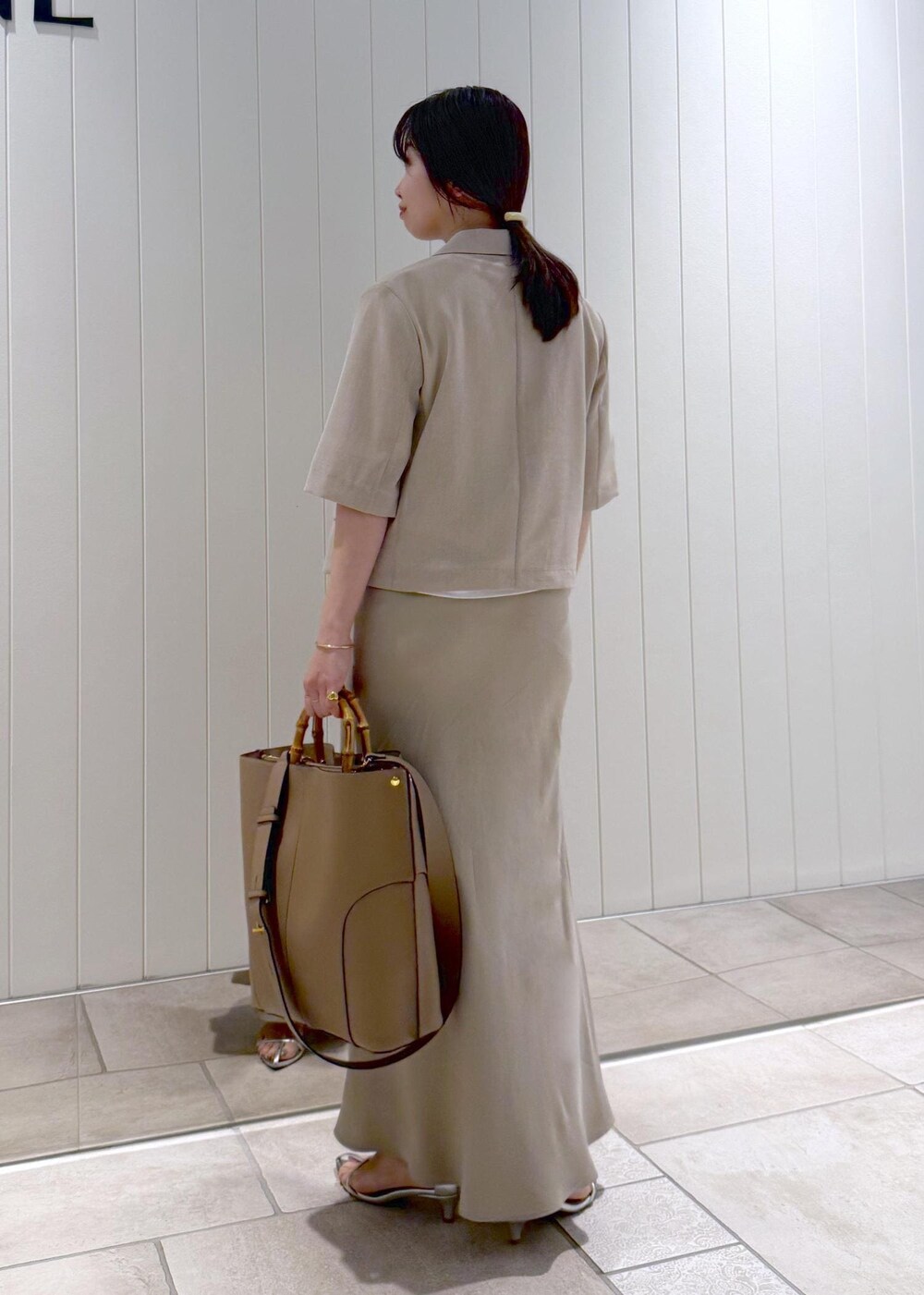 ベージュ系のトートバッグ、ホワイト系のTシャツ/カットソー、ベージュ系のスカートを着用したレディースの春コーディネートの2枚目の写真