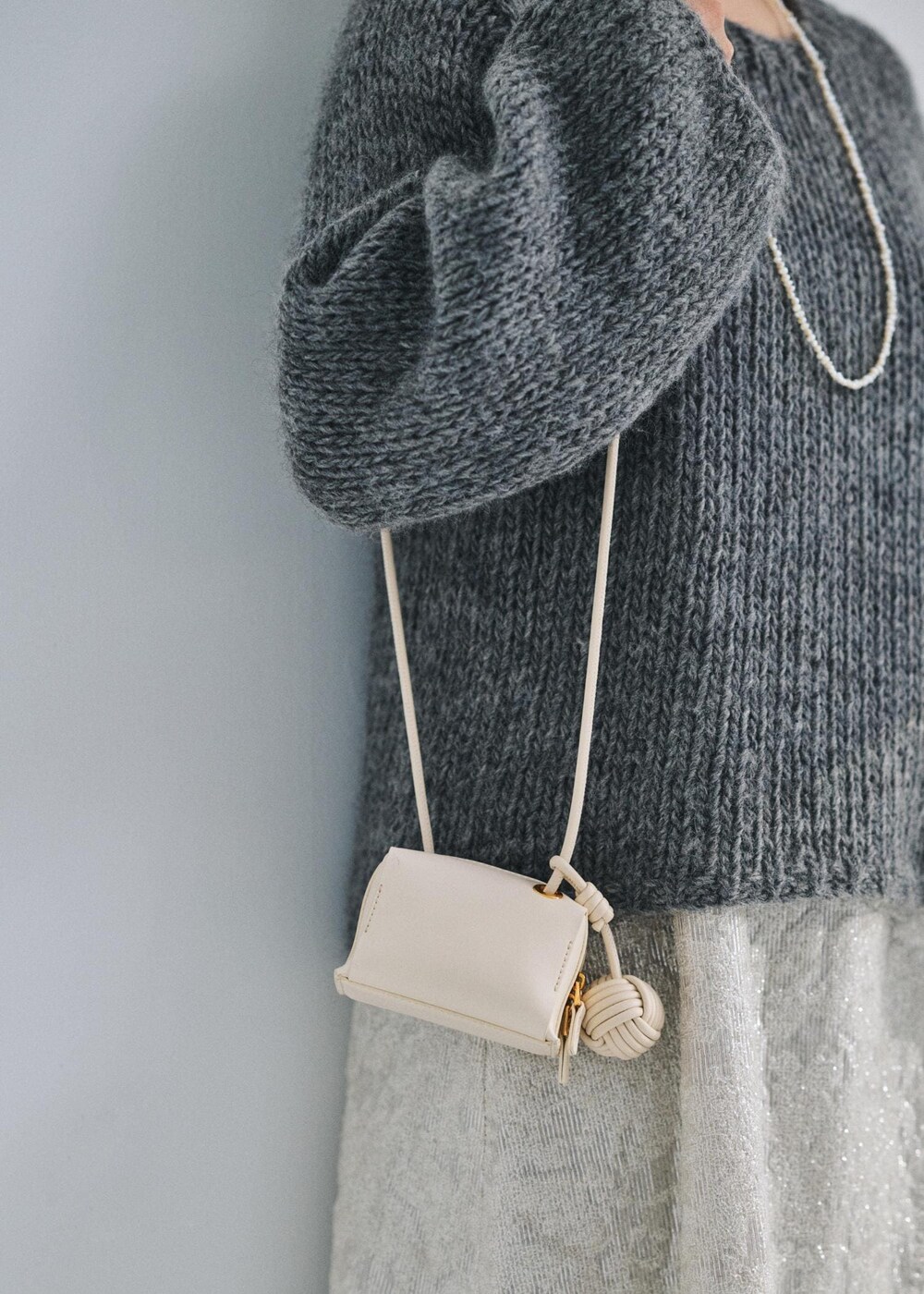 ホワイト系のショルダーバッグ、グレー系のニット/セーター、ホワイト系のワンピースを着用したレディースの冬コーディネートの4枚目の写真